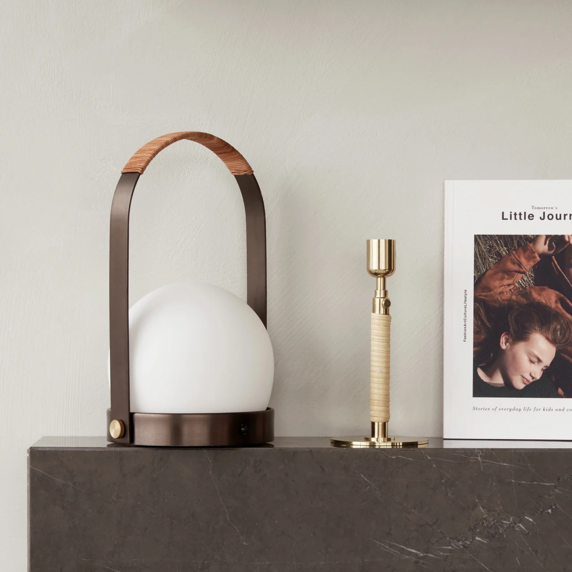 The bronzed brass Carrie Portable Table Lamp from Audo Copenhagen in a living room on top of a marble surface with other decor.