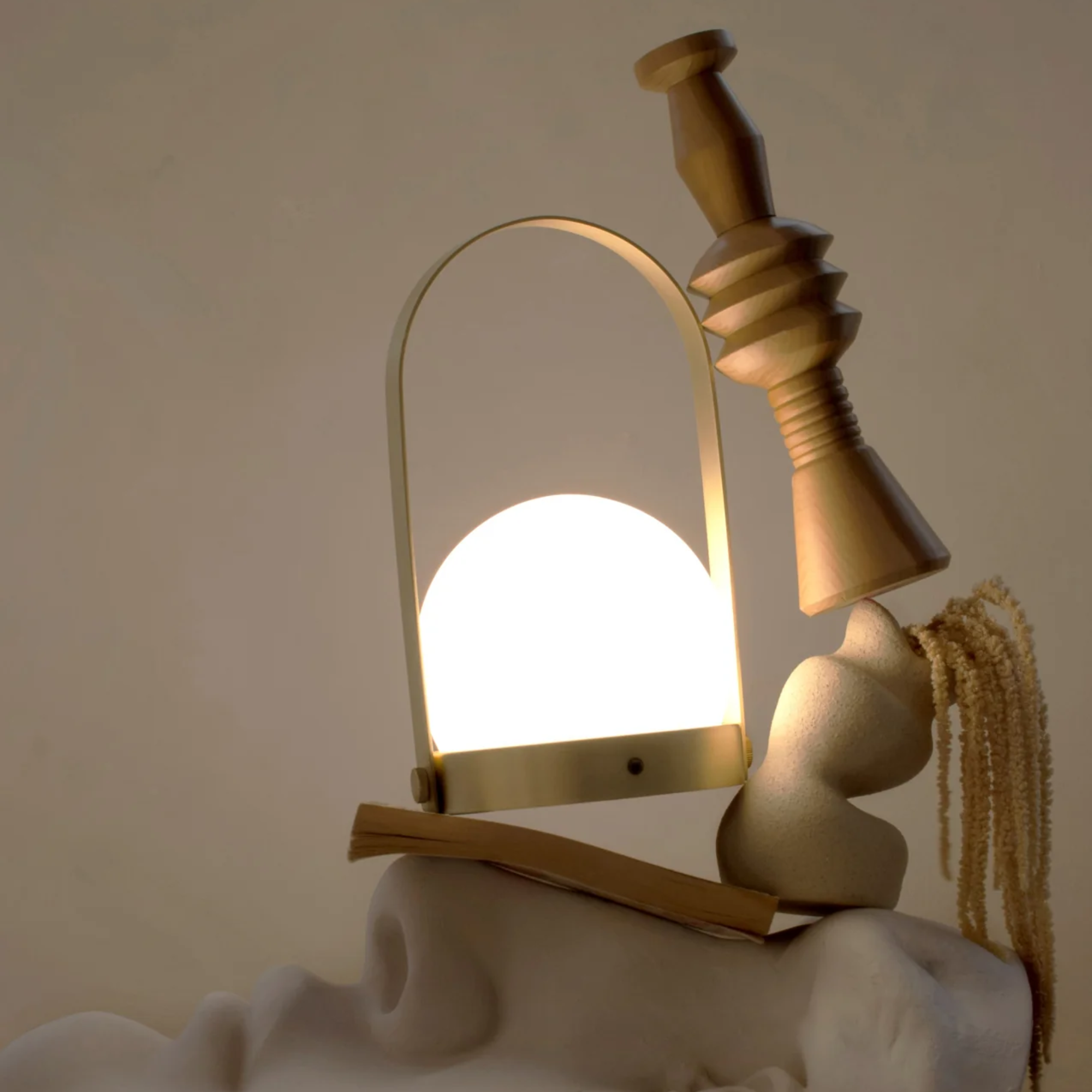 The brushed brass Carrie Portable Table Lamp from Audo Copenhagen in a lounge with various decor and sculptures.