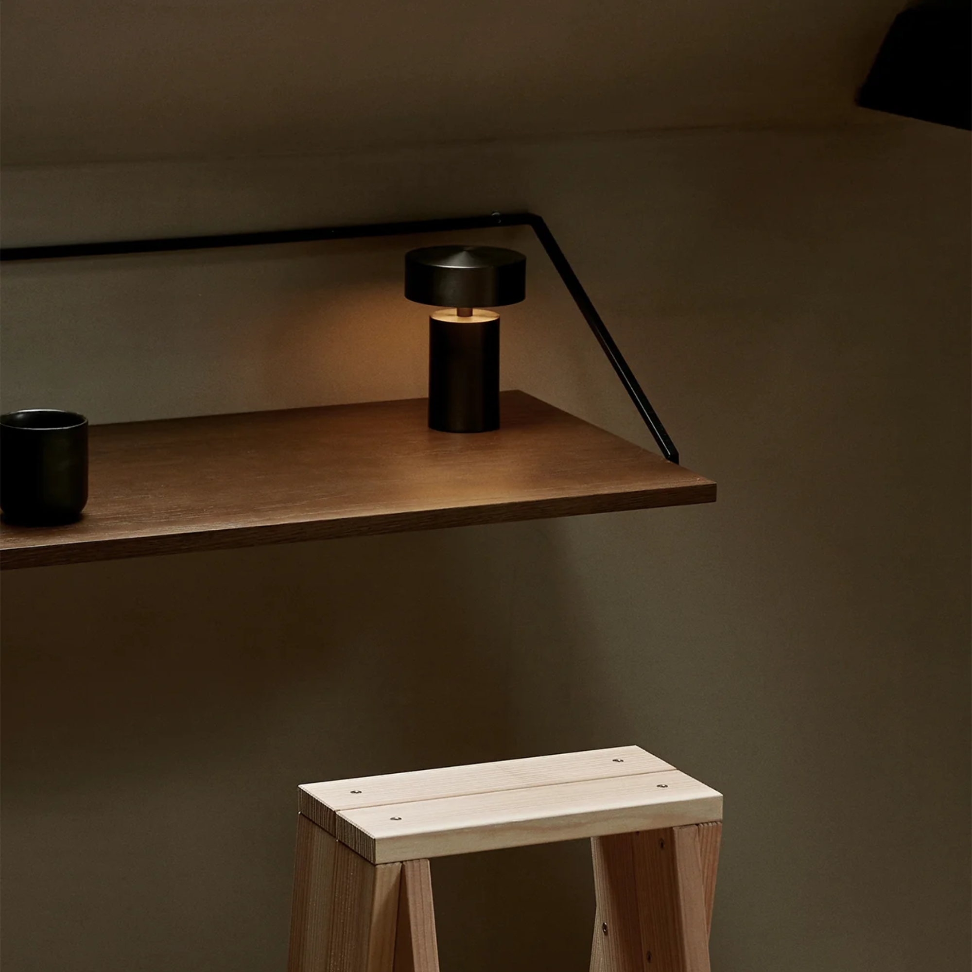 The bronze Column Portable Table Lamp from Audo Copenhagen on a floating office desk in an office.