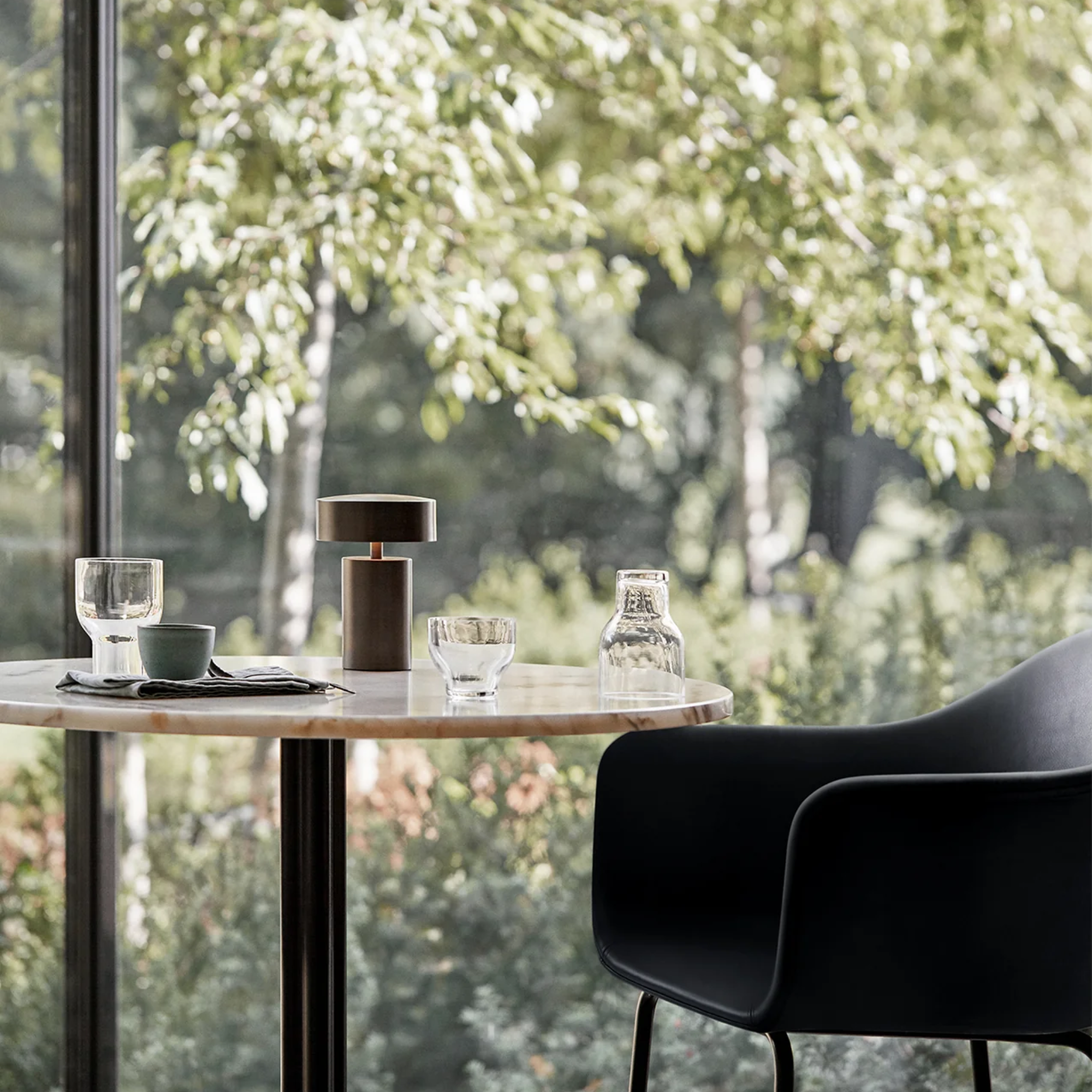 The bronze Column Portable Table Lamp from Audo Copenhagen in a restaurant on a table.