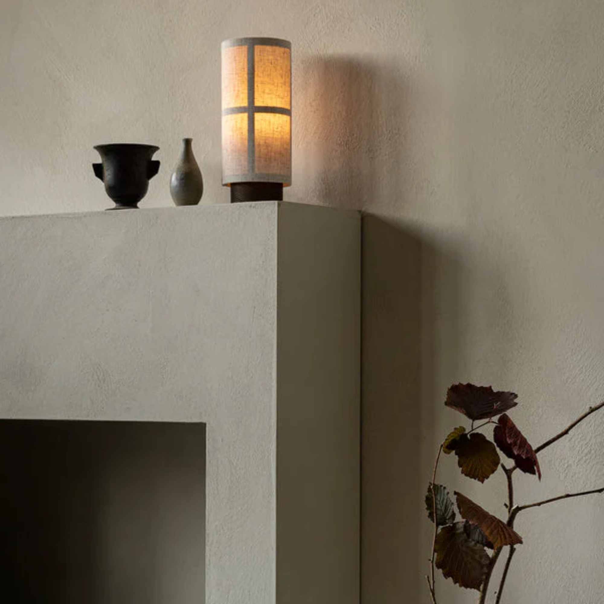 The Hashira Portable Table Lamp from Audo Copenhagen in a family area on top of a fireplace.