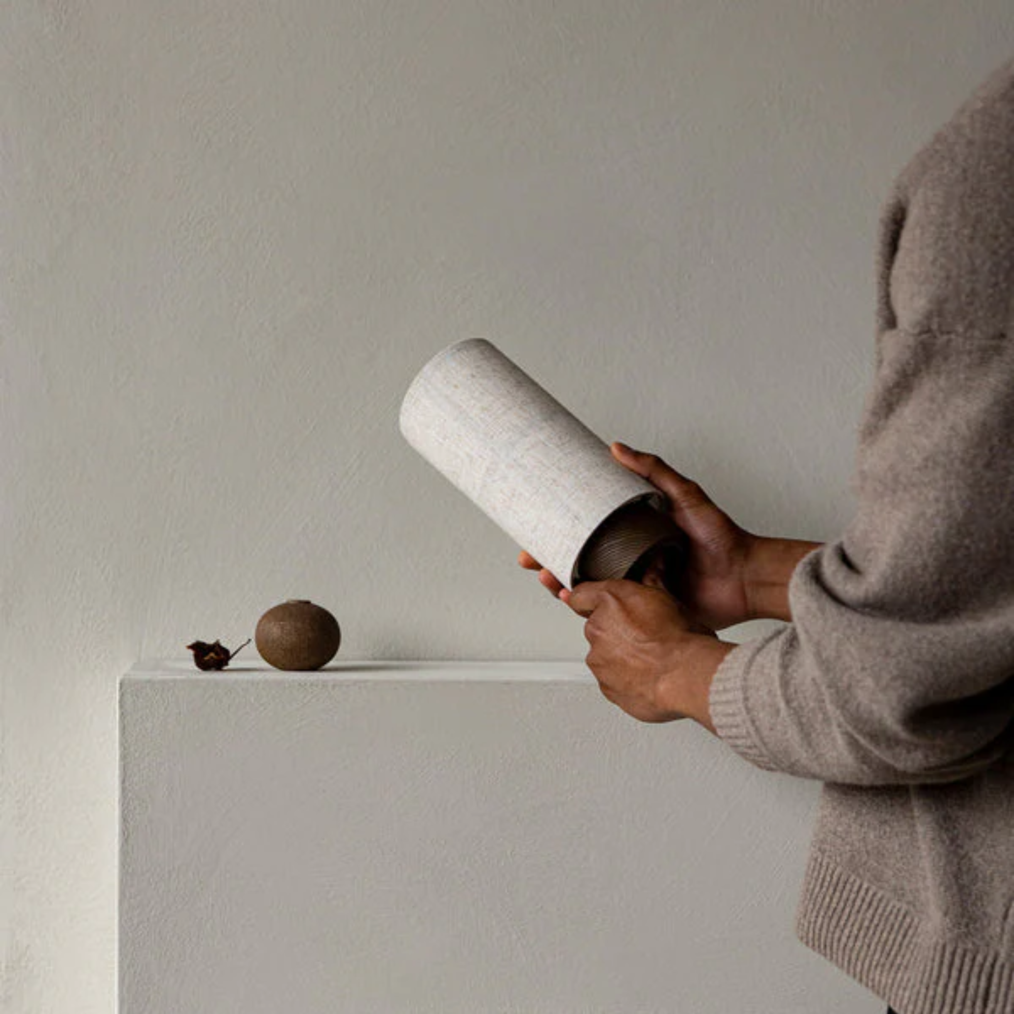 The Hashira Portable Table Lamp from Audo Copenhagen in a primary bedroom with other decor, being turned on by a model.