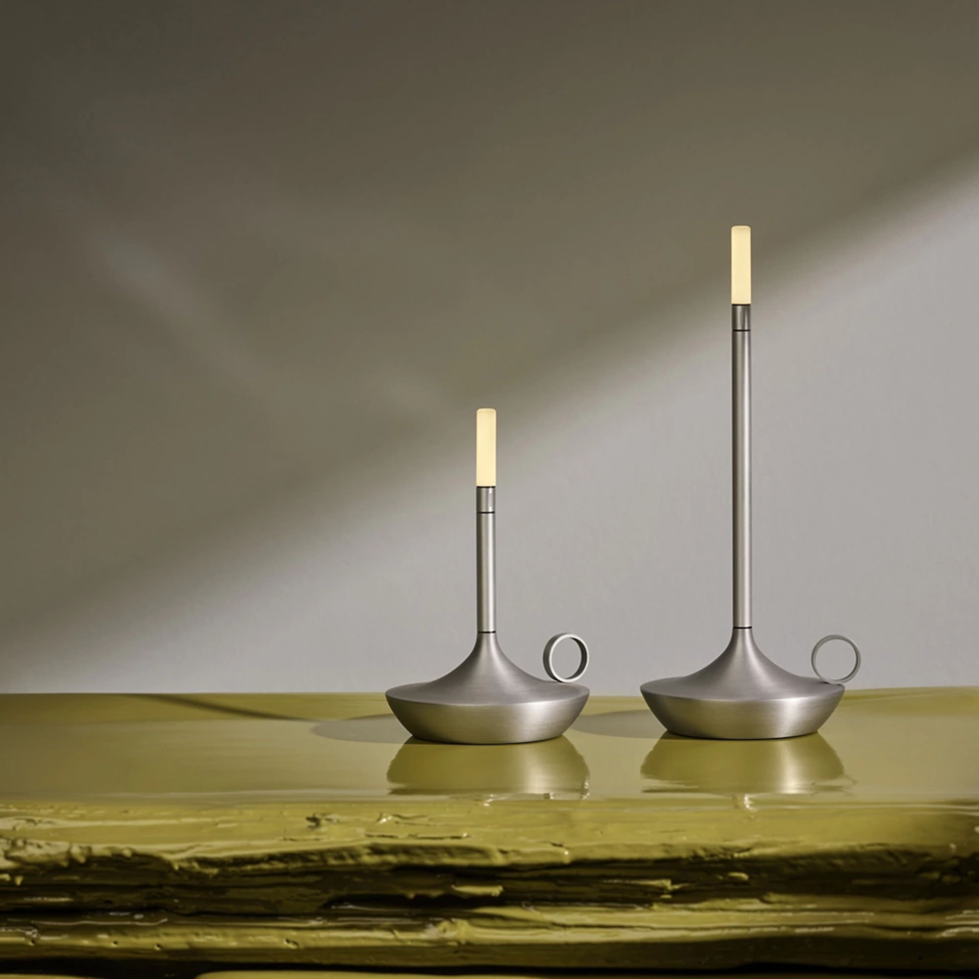 The aluminum Wick Cordless Lamp from Graypants in a lounge, showing the small and large portable light side by side. all-groups