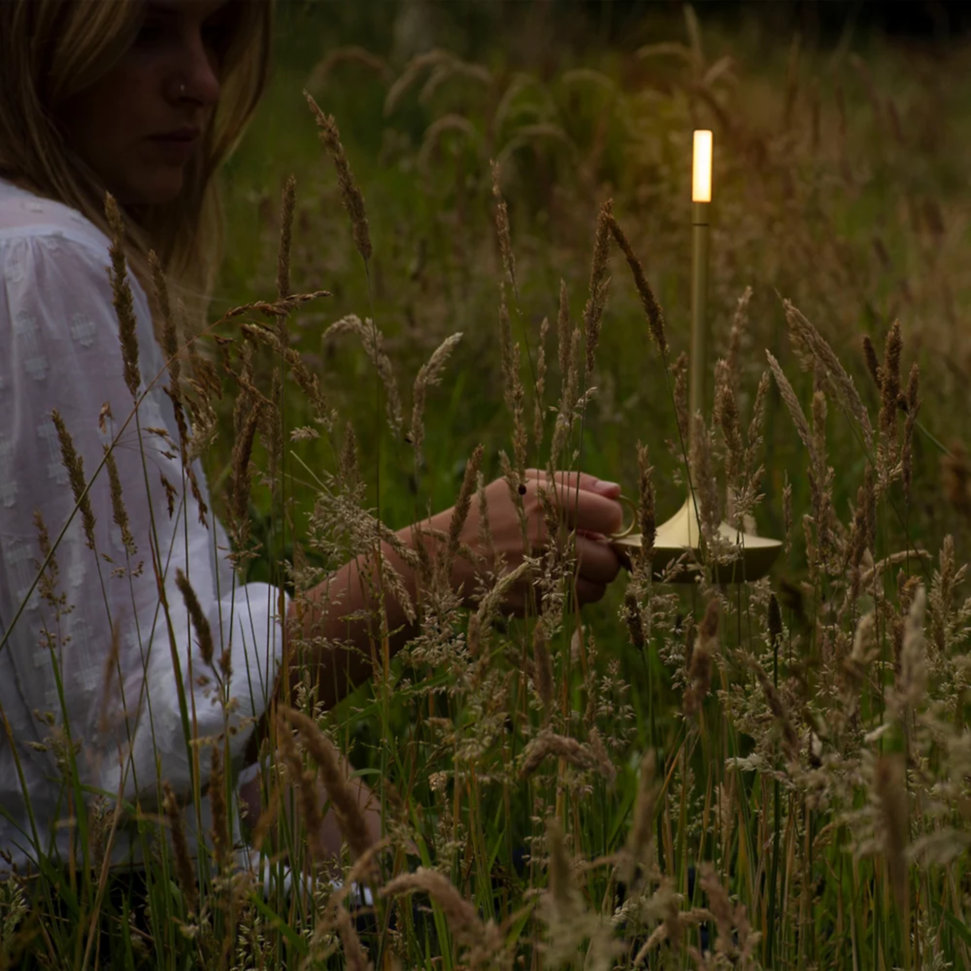 The brass Wick Cordless Lamp from Graypants in a garden.