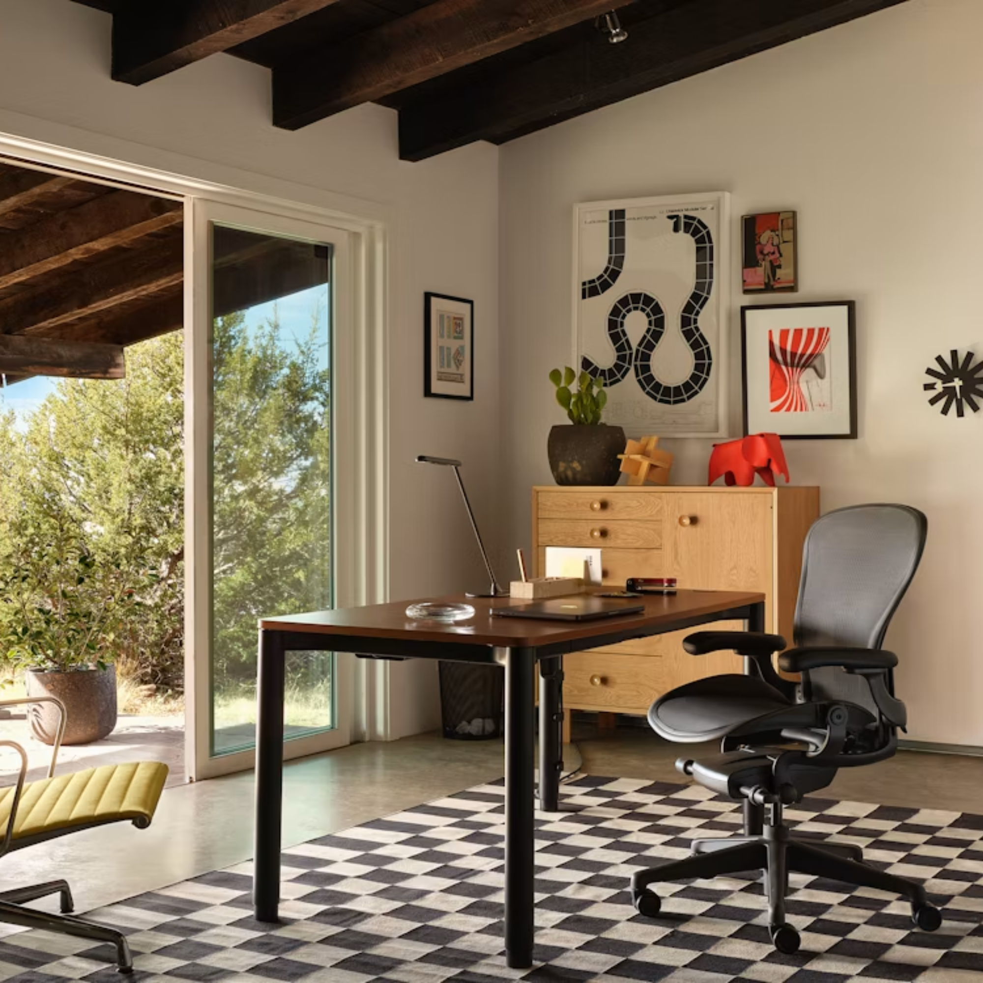 The Aeron Office Chair from Herman Miller shown in a family area in front of a desk with a laptop, with a storage unit in the corner.