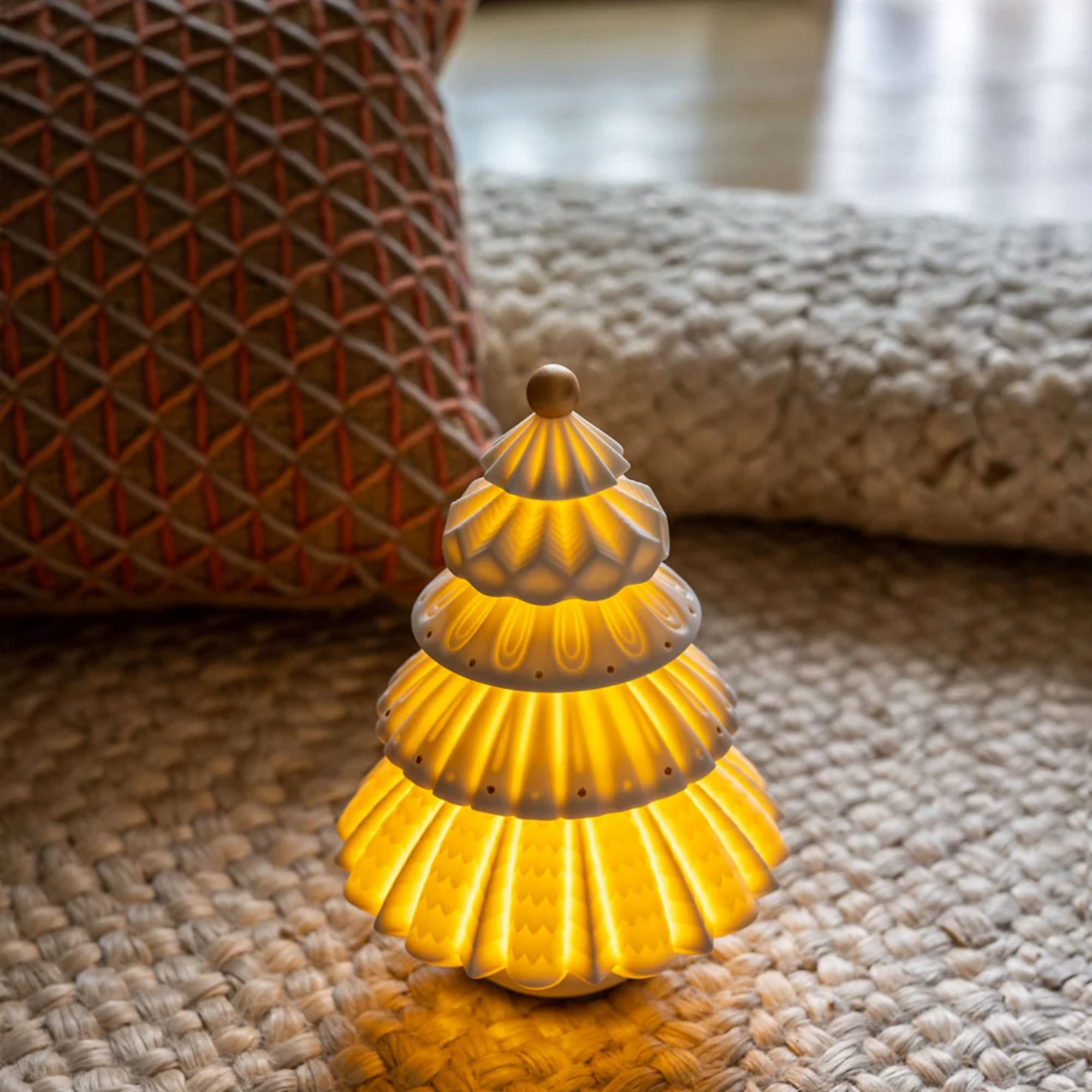 The Christmas Tree Cordless Table Lamp from Lladro in a living room on top of a rug.