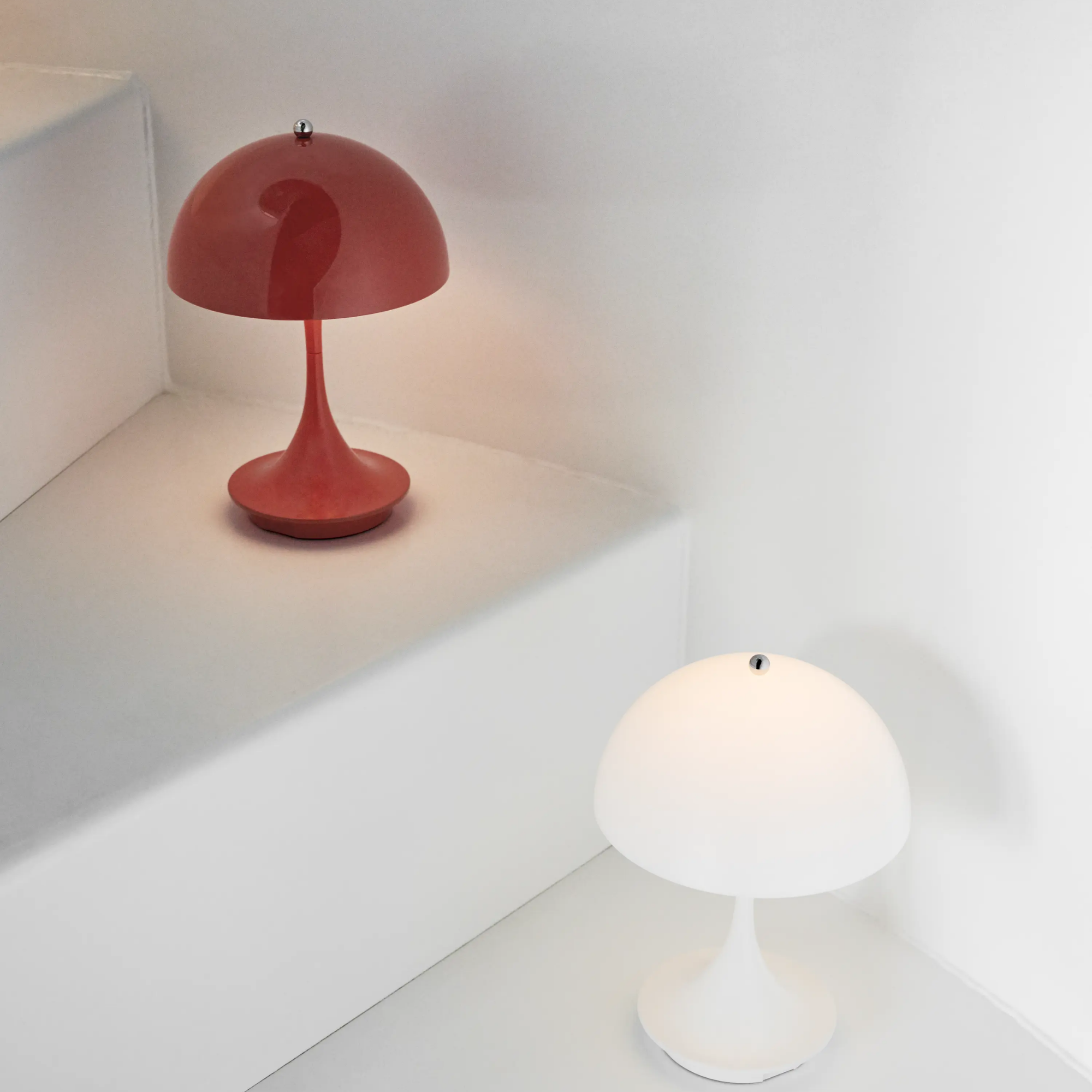 The coral Panthella 160 Portable Lamp from Louis Poulsen in a stairway with the white color option.