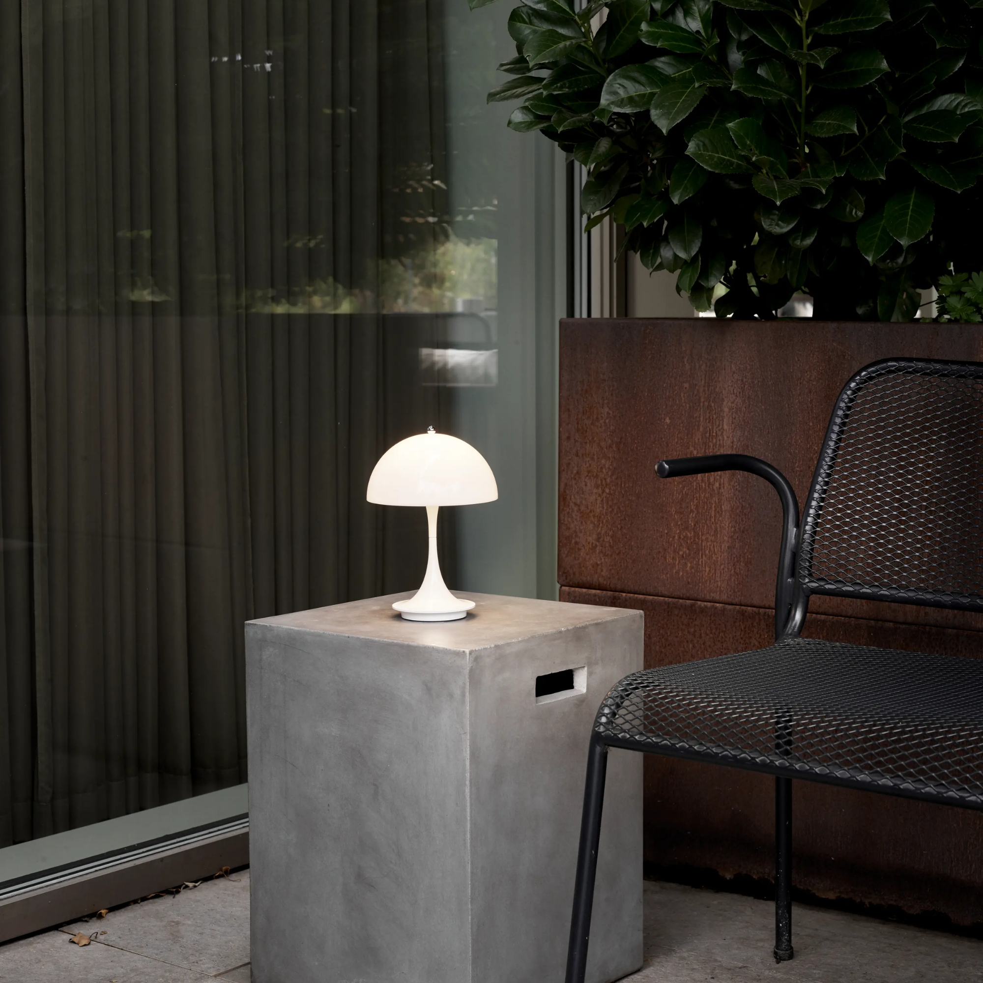 The opal Panthella 160 Portable Lamp from Louis Poulsen in a living space beside a black chair.