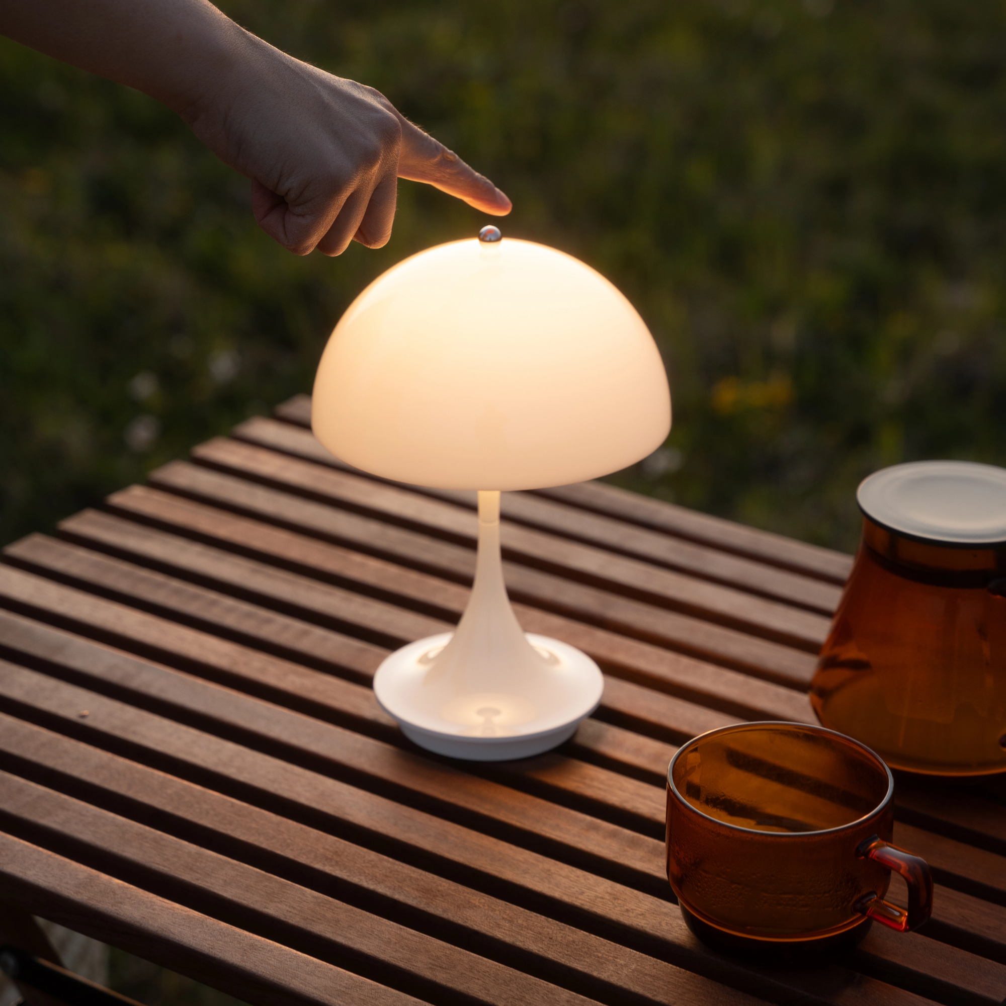 The opal Panthella 160 Portable Lamp from Louis Poulsen in an outdoor lounge on top of a table.