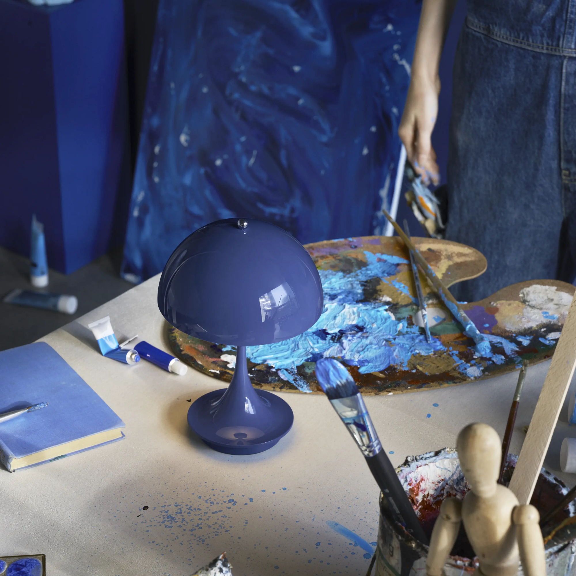 The opaque indigo Panthella 160 Portable Lamp from Louis Poulsen in an art studio.