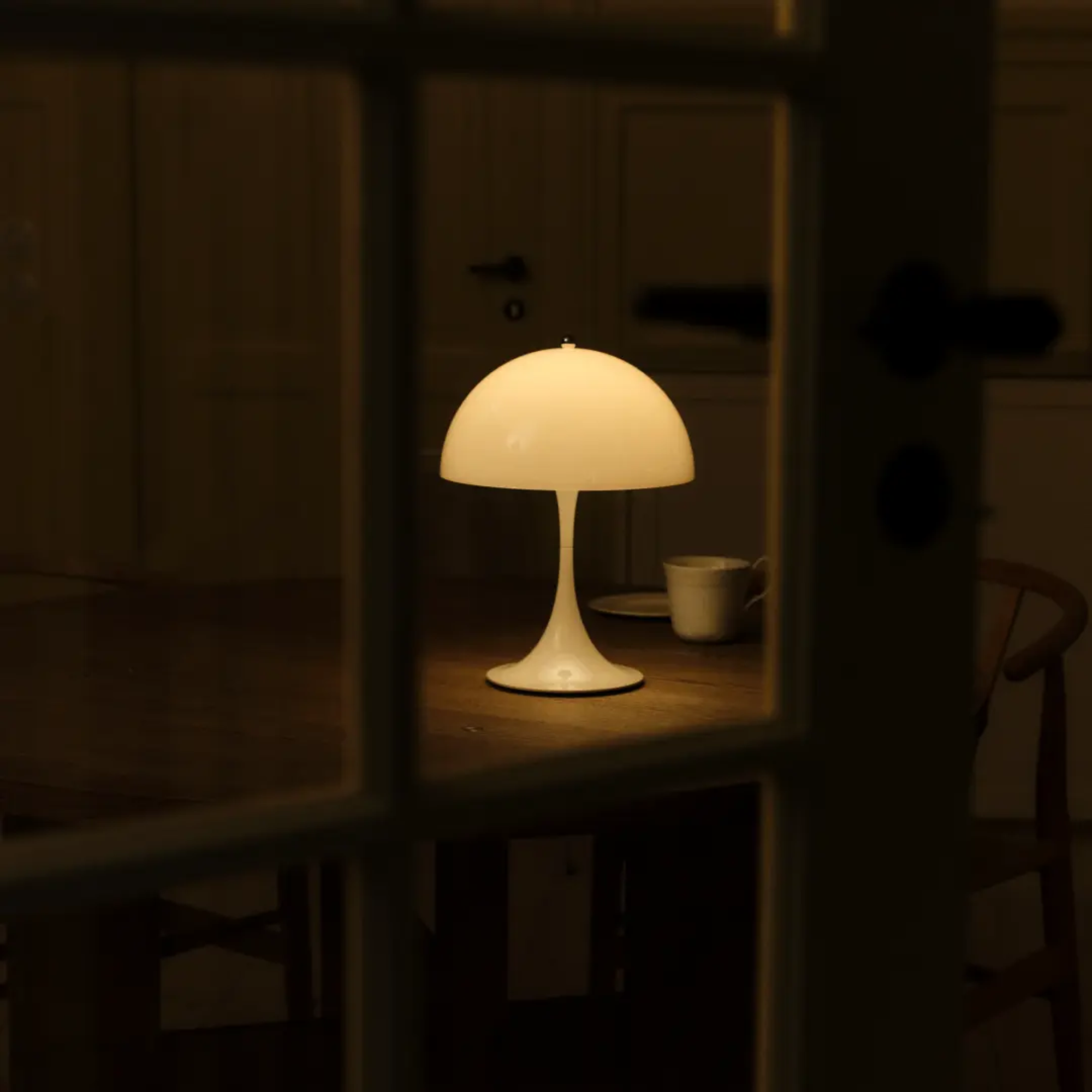 The opal Panthella 250 Portable Lamp from Louis Poulsen in a dining room on a table.