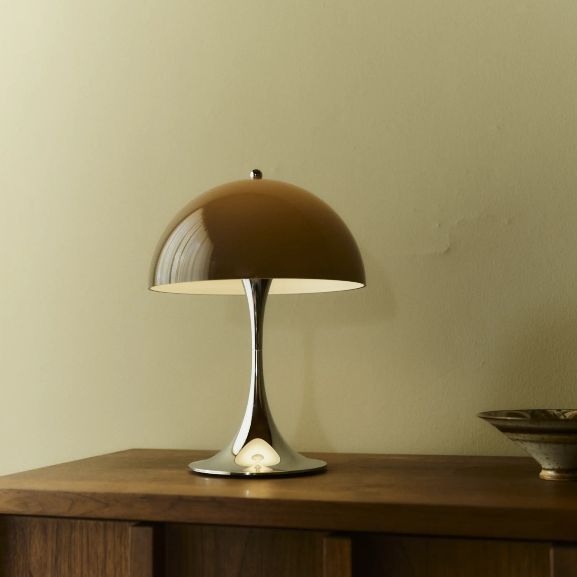 The 13.2 inch brown Panthella Portable Lamp: The Originals from Louis Poulsen in a primary bedroom on a wooden console.