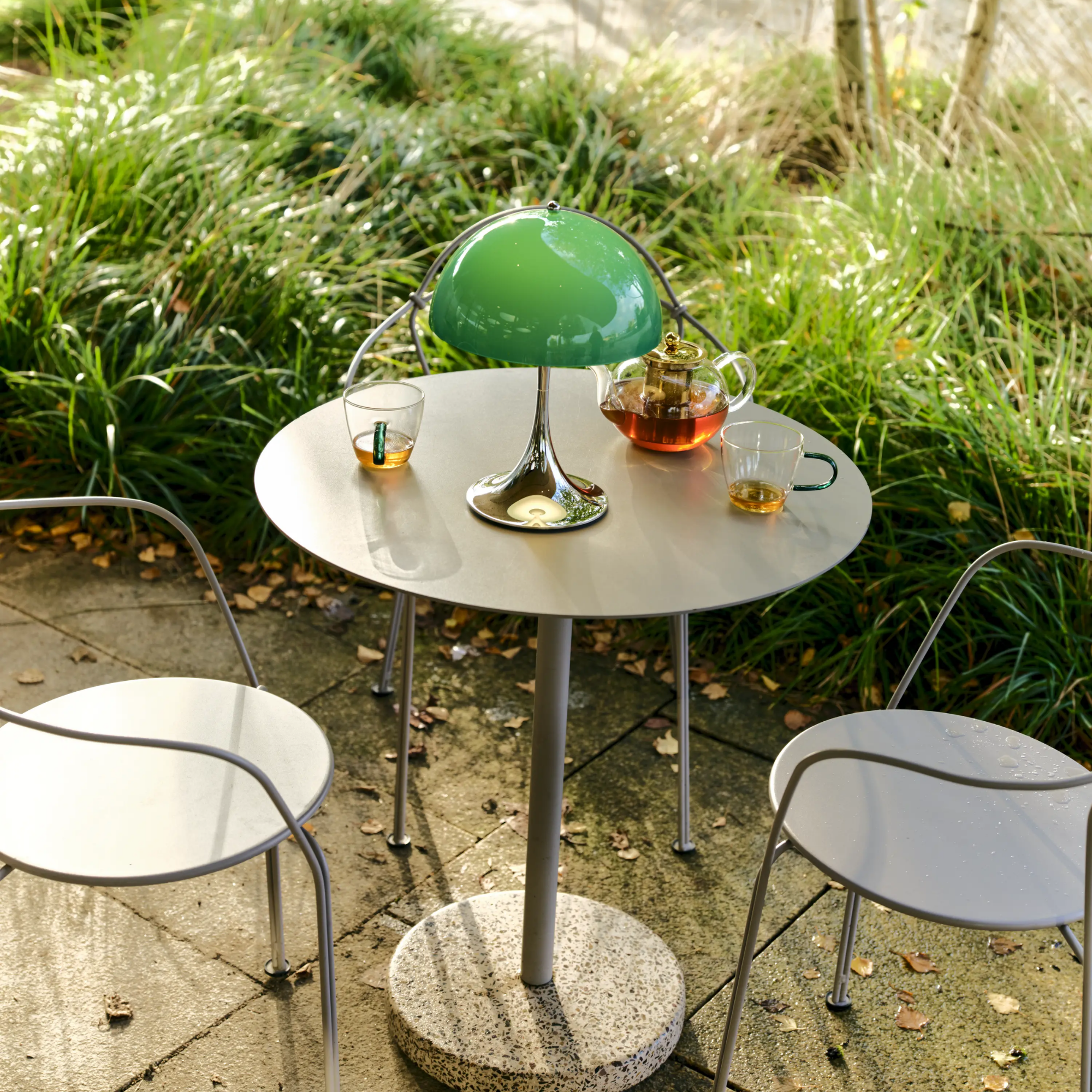 The 13.2 inch green Panthella Portable Lamp: The Originals from Louis Poulsen in an outdoor cafe dining setting with tea.