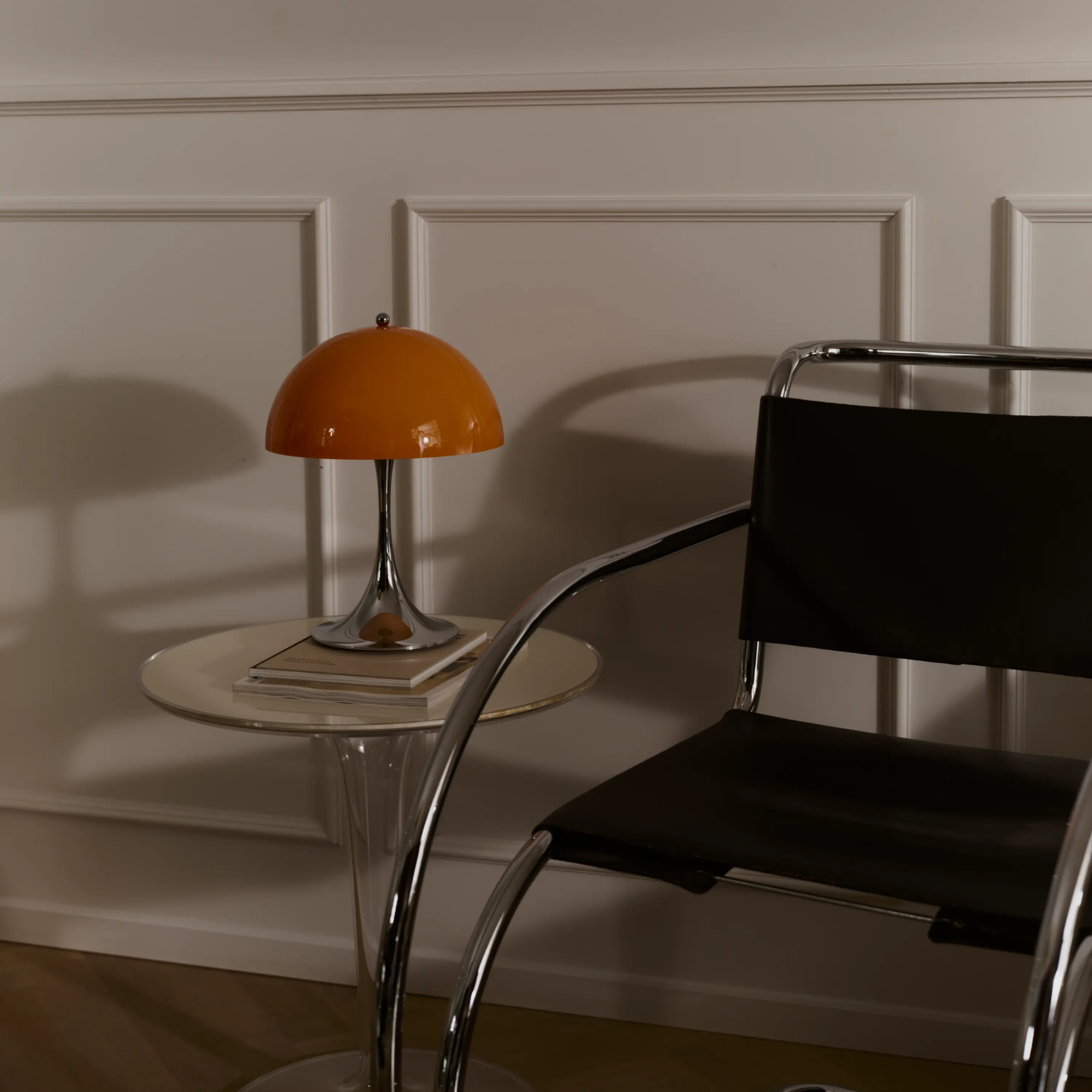 The 13.2 inch orange Panthella Portable Lamp: The Originals from Louis Poulsen in a living room next to a chair.