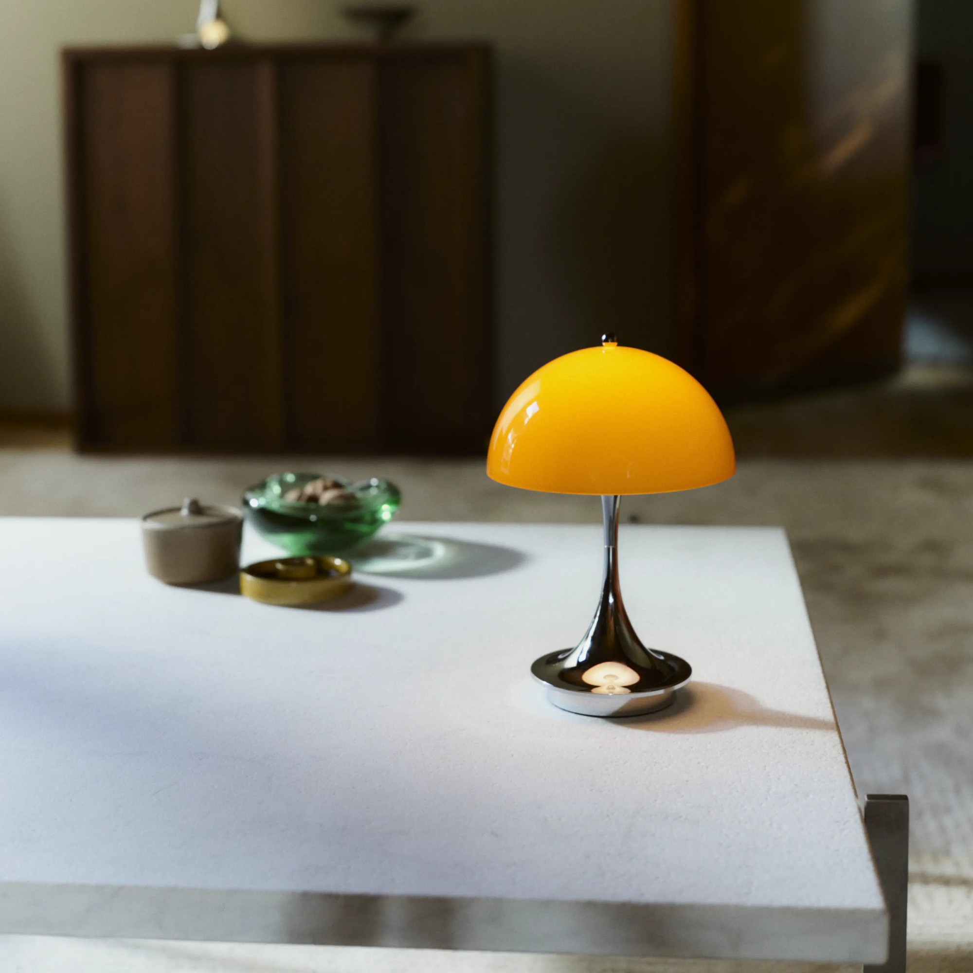 The 9.5 inch orange Panthella Portable Lamp: The Originals from Louis Poulsen in a home office on top of a table.