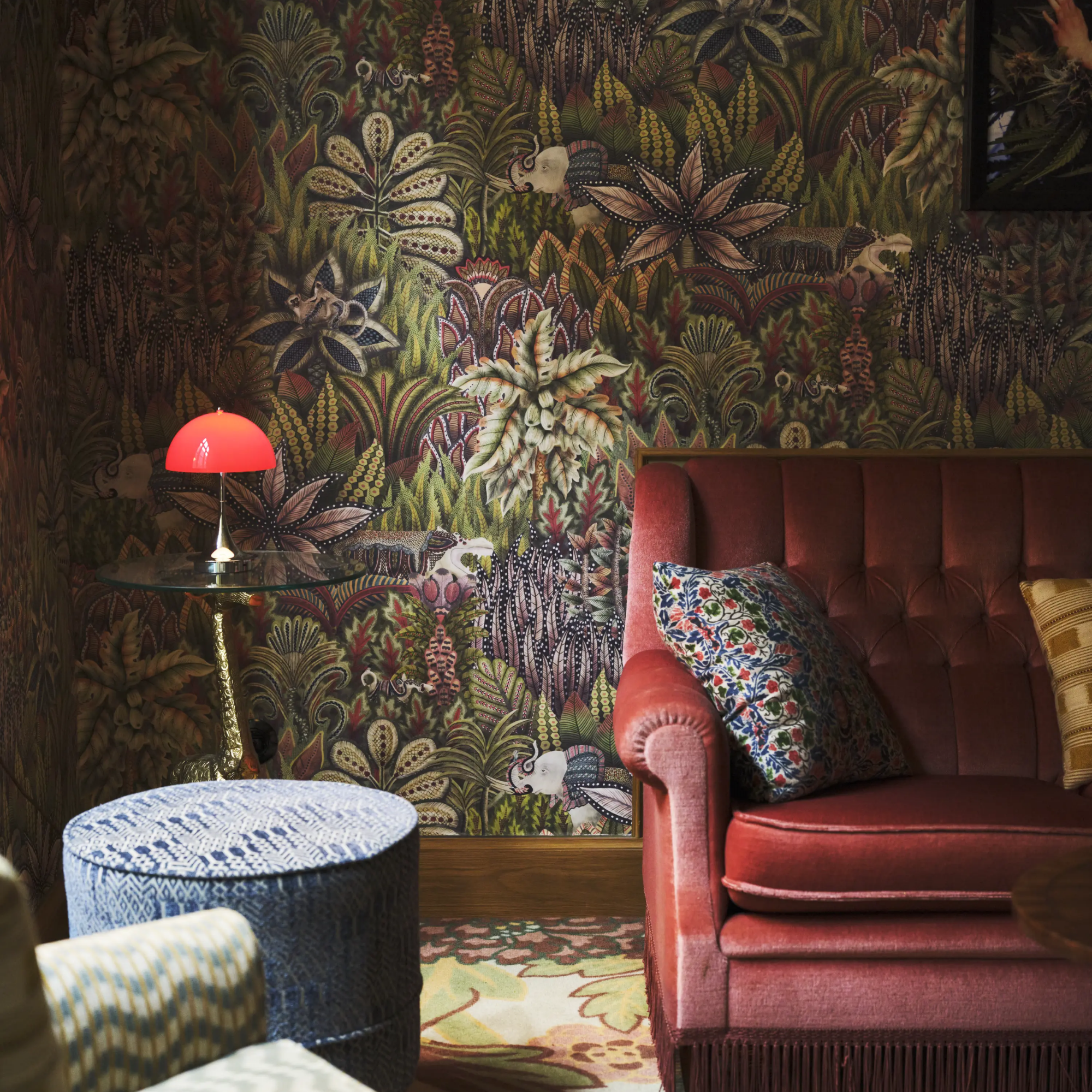 The 9.5 inch red Panthella Portable Lamp: The Originals from Louis Poulsen in a lounge with intricate wallpaper and lounge furniture.