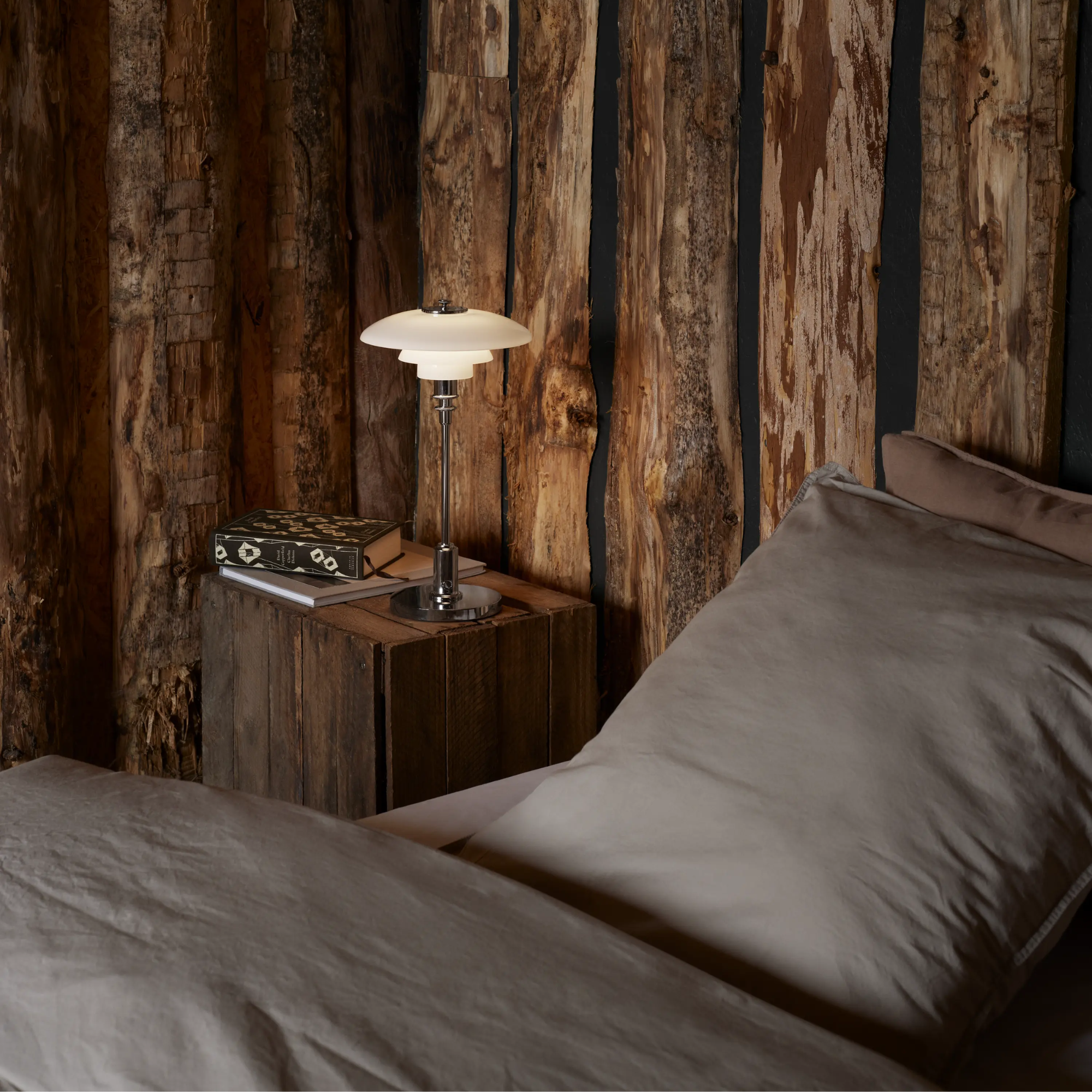 The chrome PH 2/1 Portable Lamp from Louis Poulsen in a guest bedroom beside the bed.