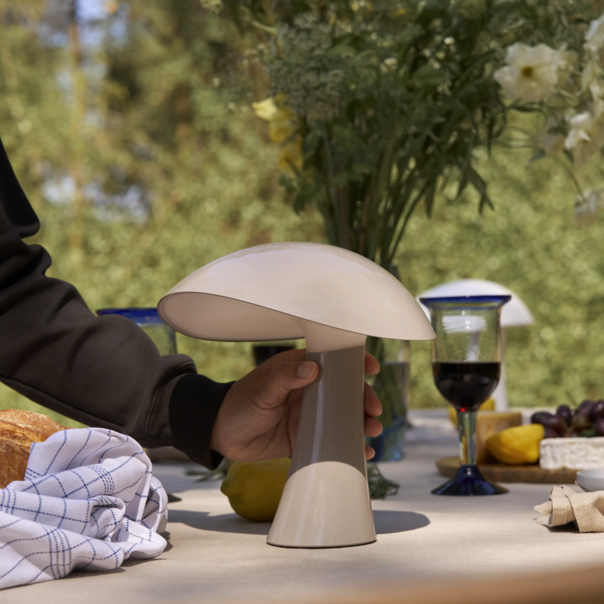 The earth gray Rumee 220 Portable Lamp from Louis Poulsen used for an outdoor picnic.