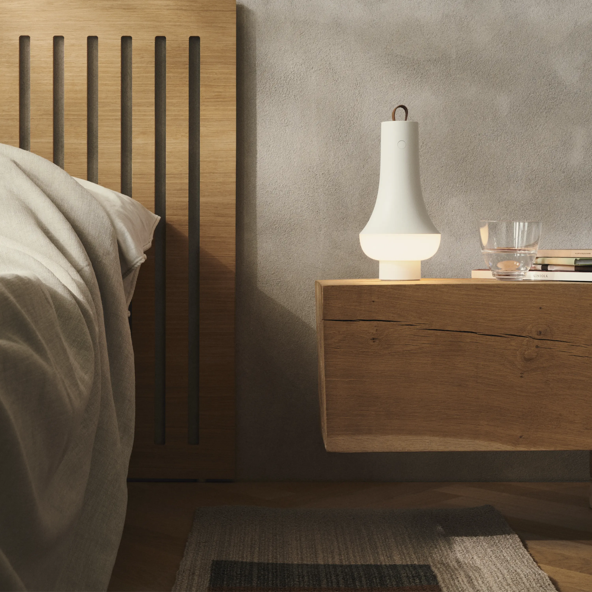 The white Tomoshi Portable Lamp from Louis Poulsen in a primary bedroom on top of a bedside table.