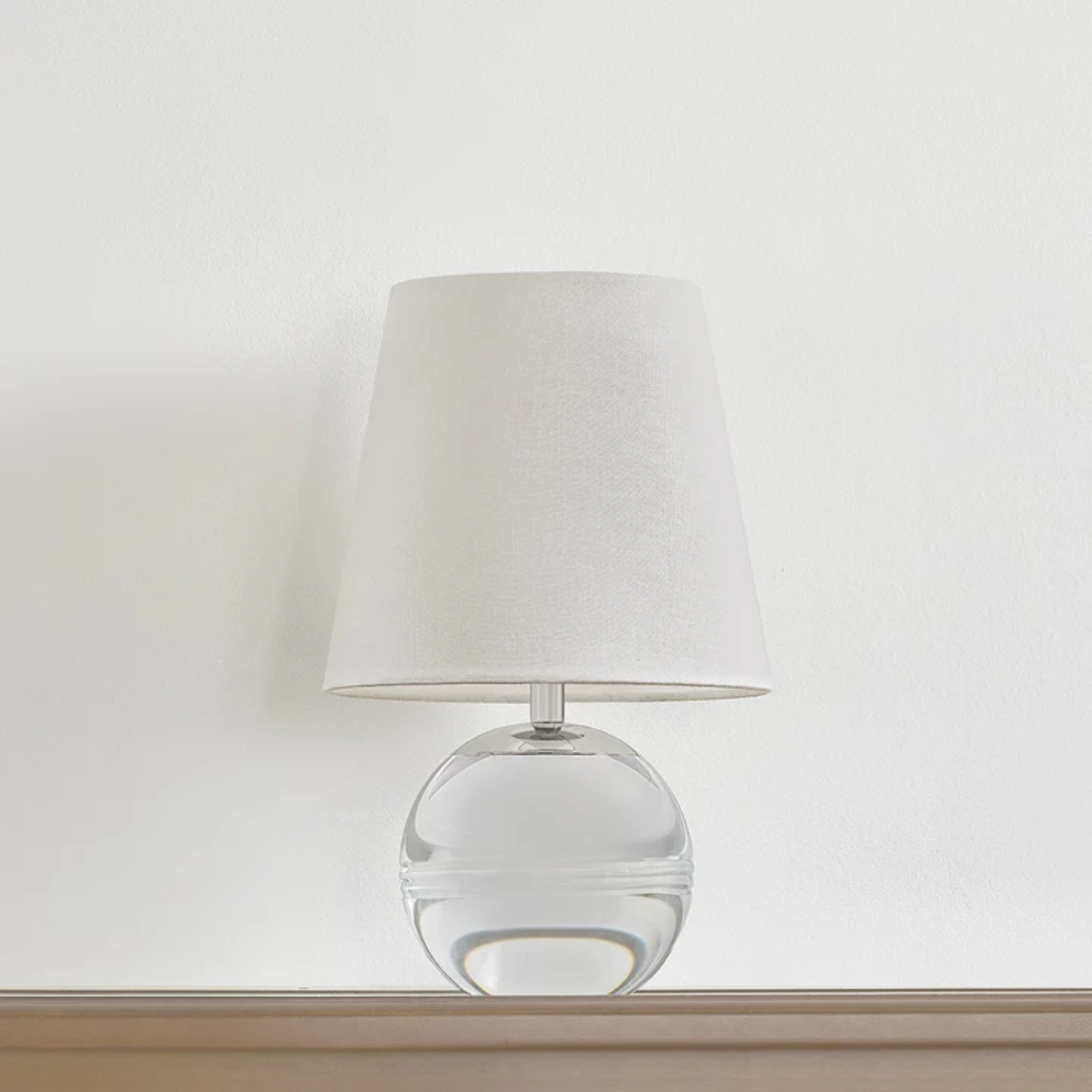 The Nicole Rechargeable LED Table Lamp from Mitzi in a bedroom on top of a wood surface.