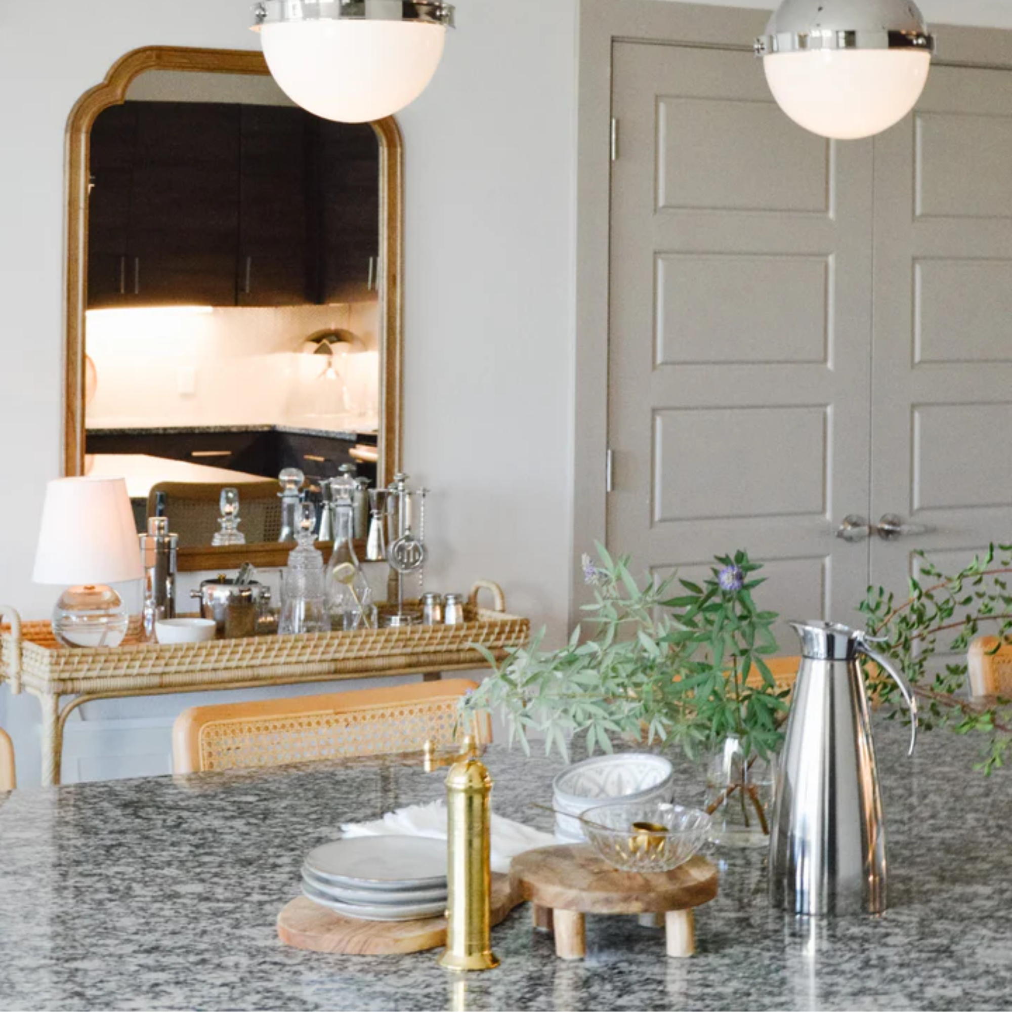 The Nicole Rechargeable LED Table Lamp from Mitzi on top of an end table in a kitchen and dining space.