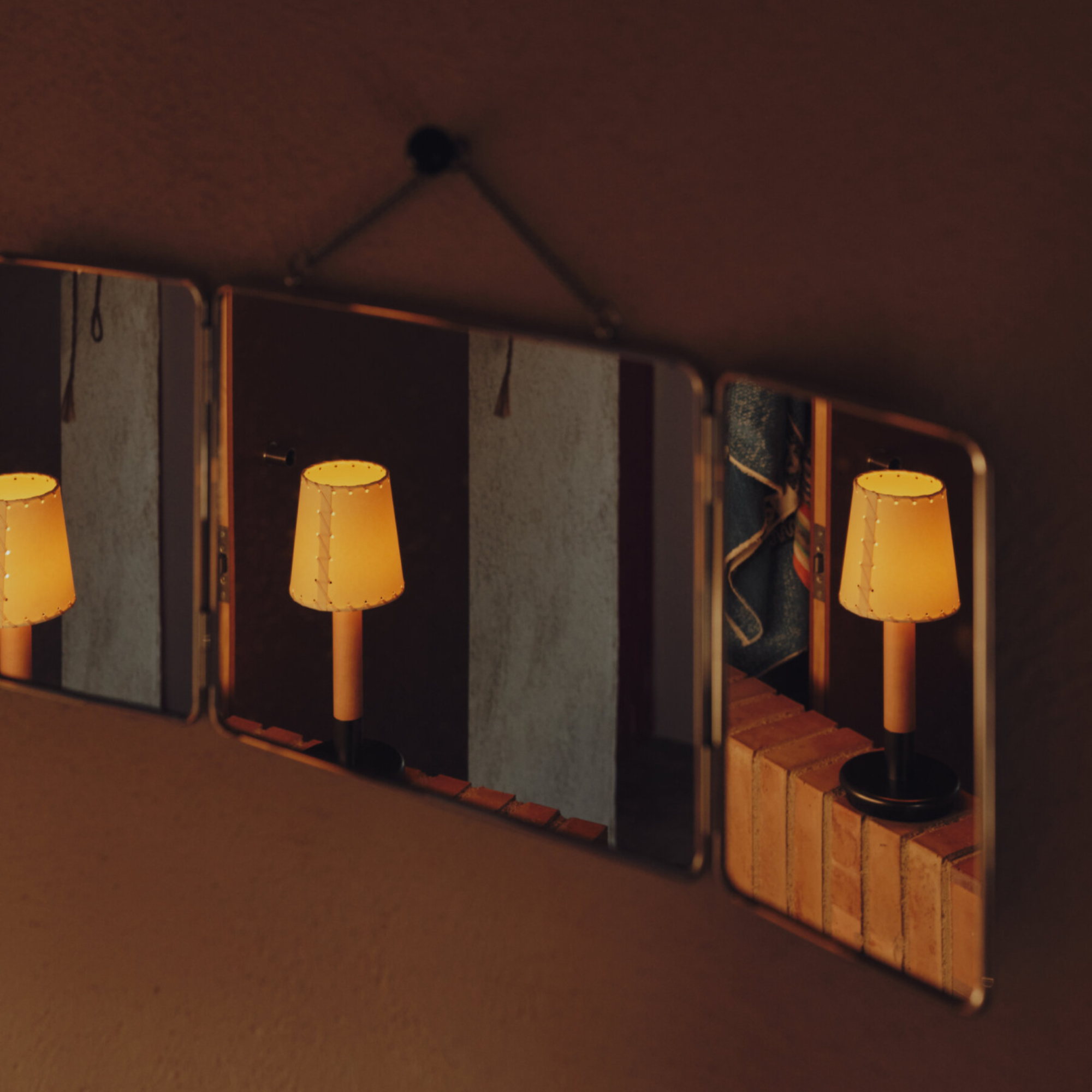 The Básica Mínima Batería Cordless Lamp from Santa & Cole with the stitched beige parchment shade in a bedroom, reflected in the mirror.