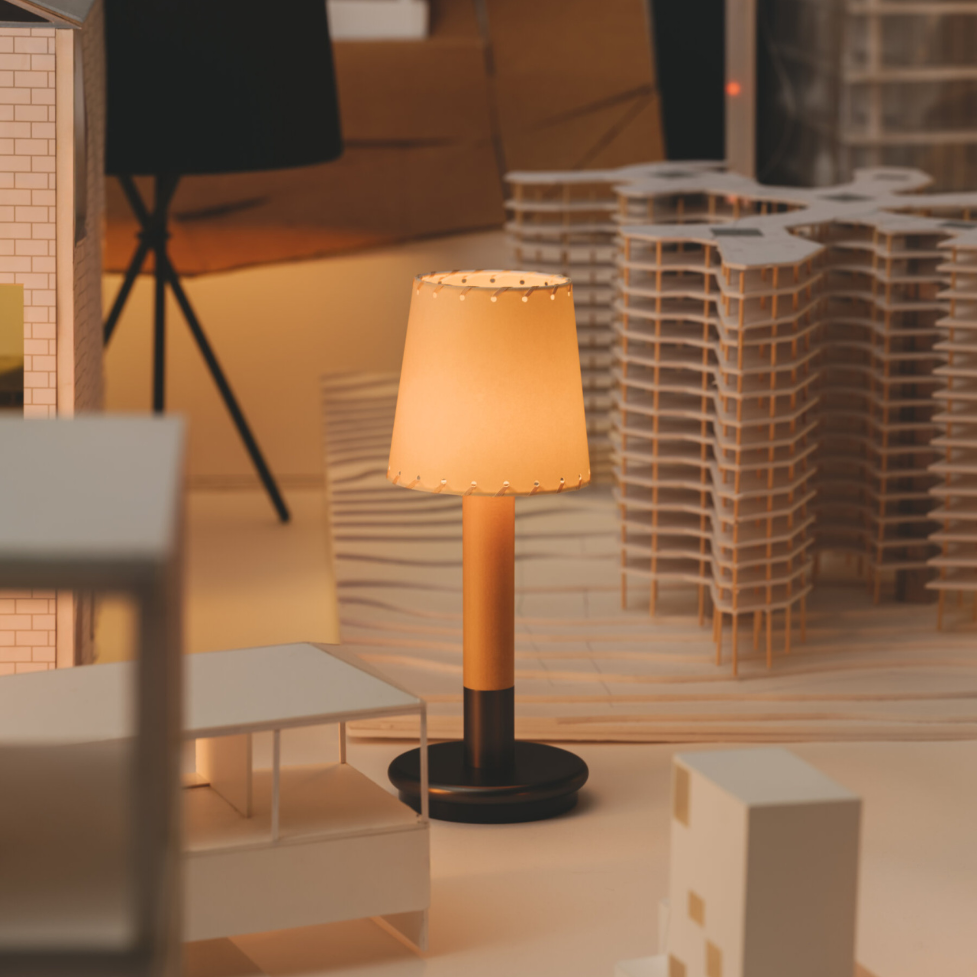 The Básica Mínima Batería Cordless Lamp from Santa & Cole with the stitched beige parchment shade in a business space.