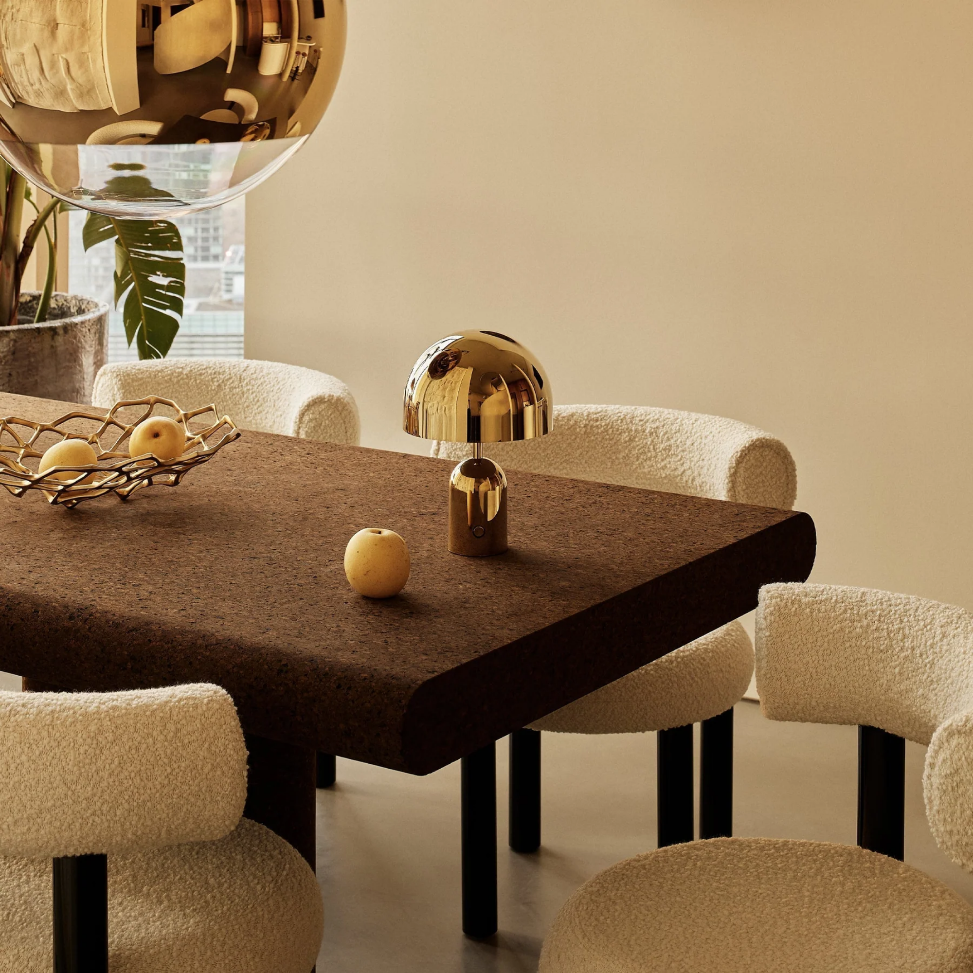 The gold Bell Cordless Lamp from Tom Dixon in a dining room on top of the dining table.