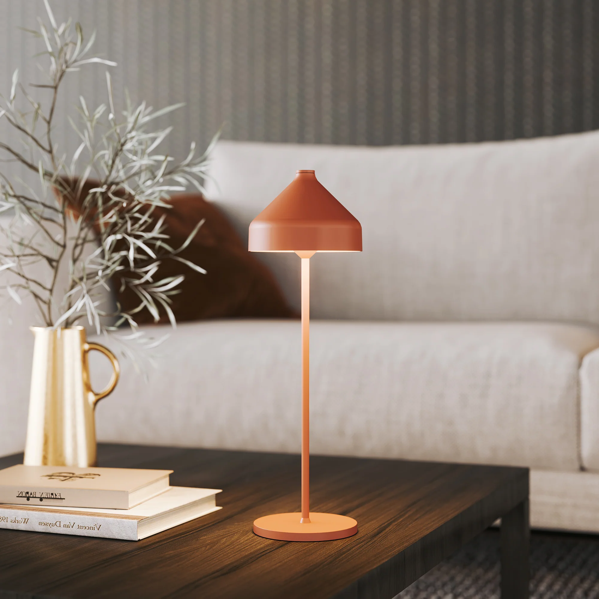The terracotta Amelie Pro Cordless Lamp from Zafferano in a living room on top of a coffee table.