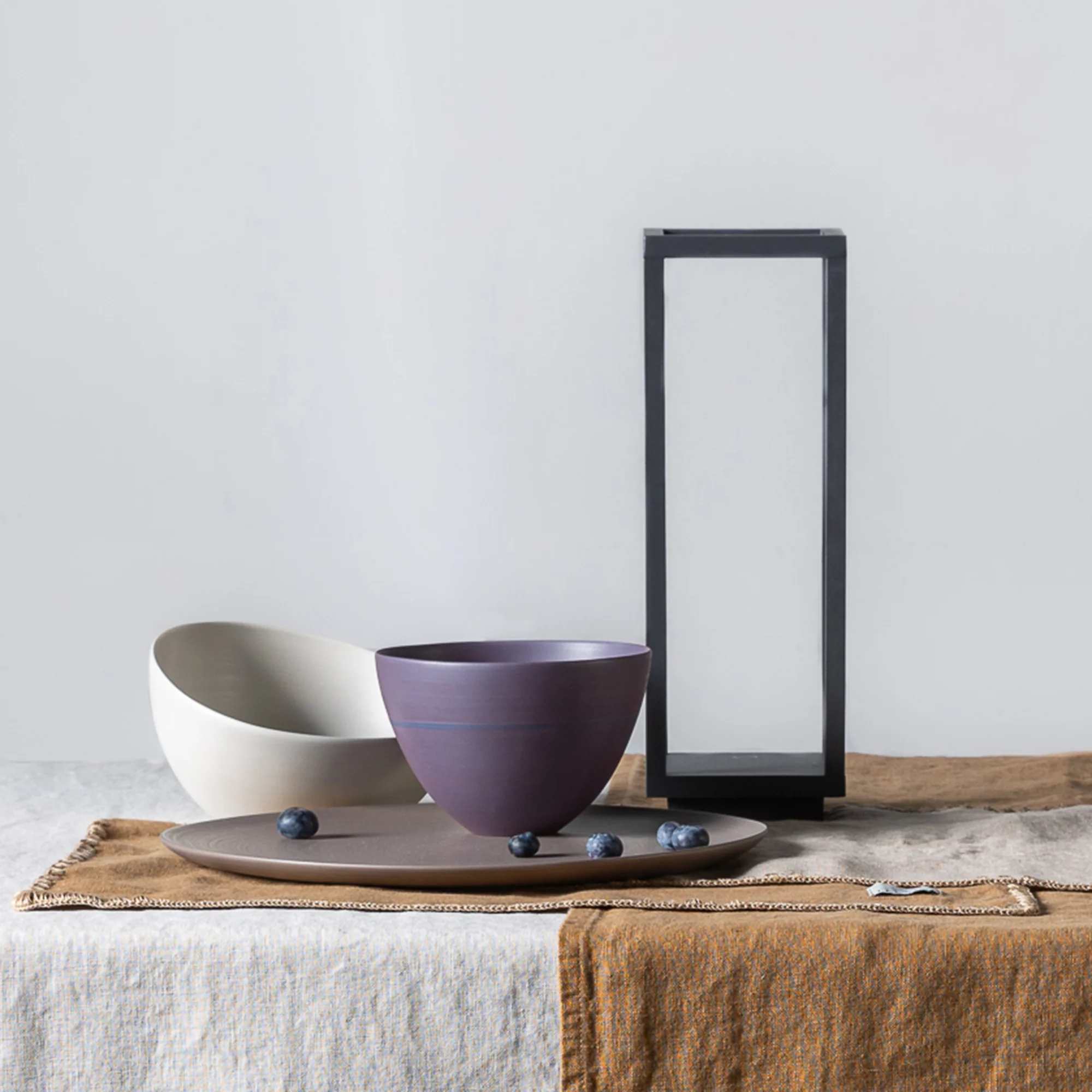 The dark gray Home Cordless Lamp from Zafferano in a dining space on top of a dining table.
