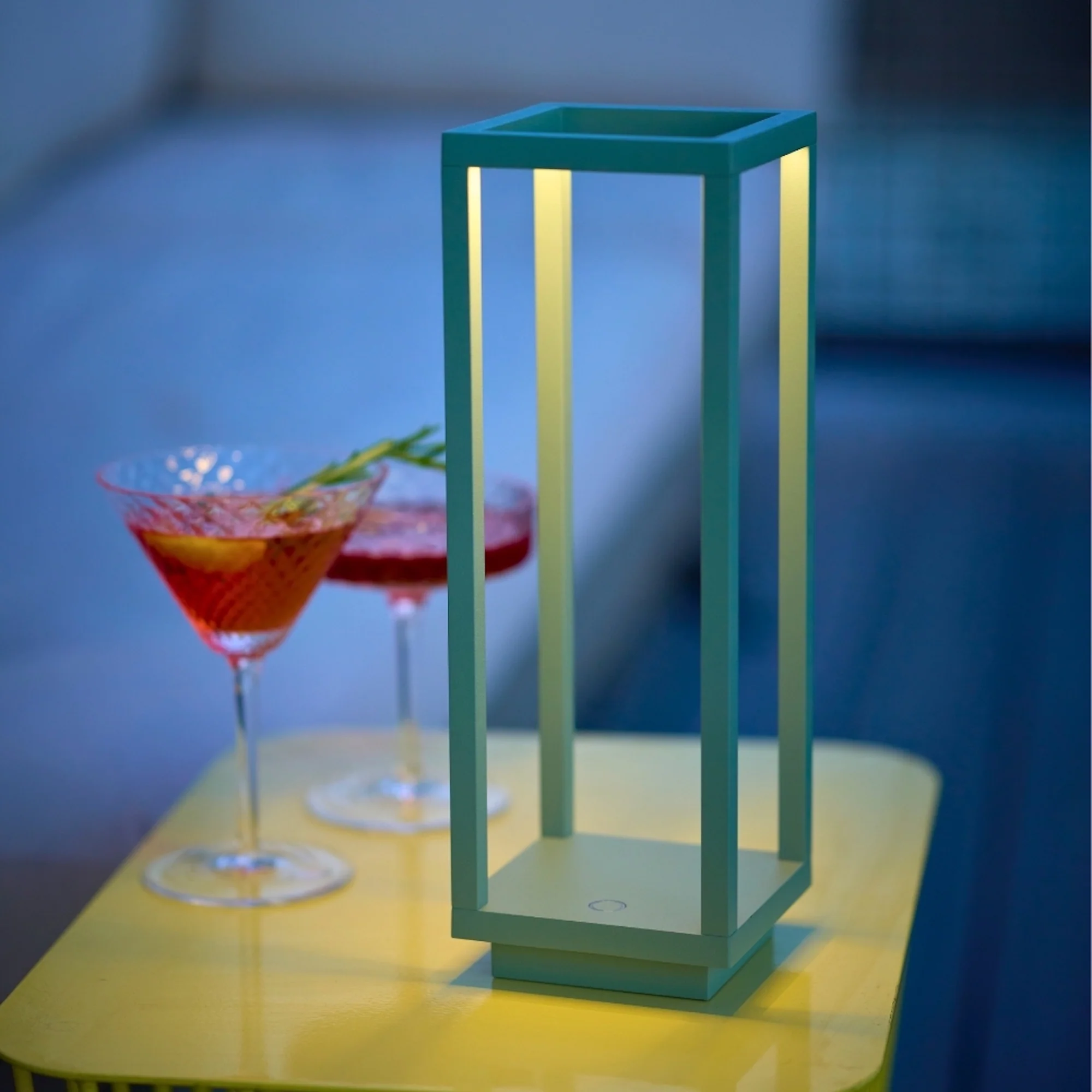 The sage Home Cordless Lamp from Zafferano in a living area on top of an end table.