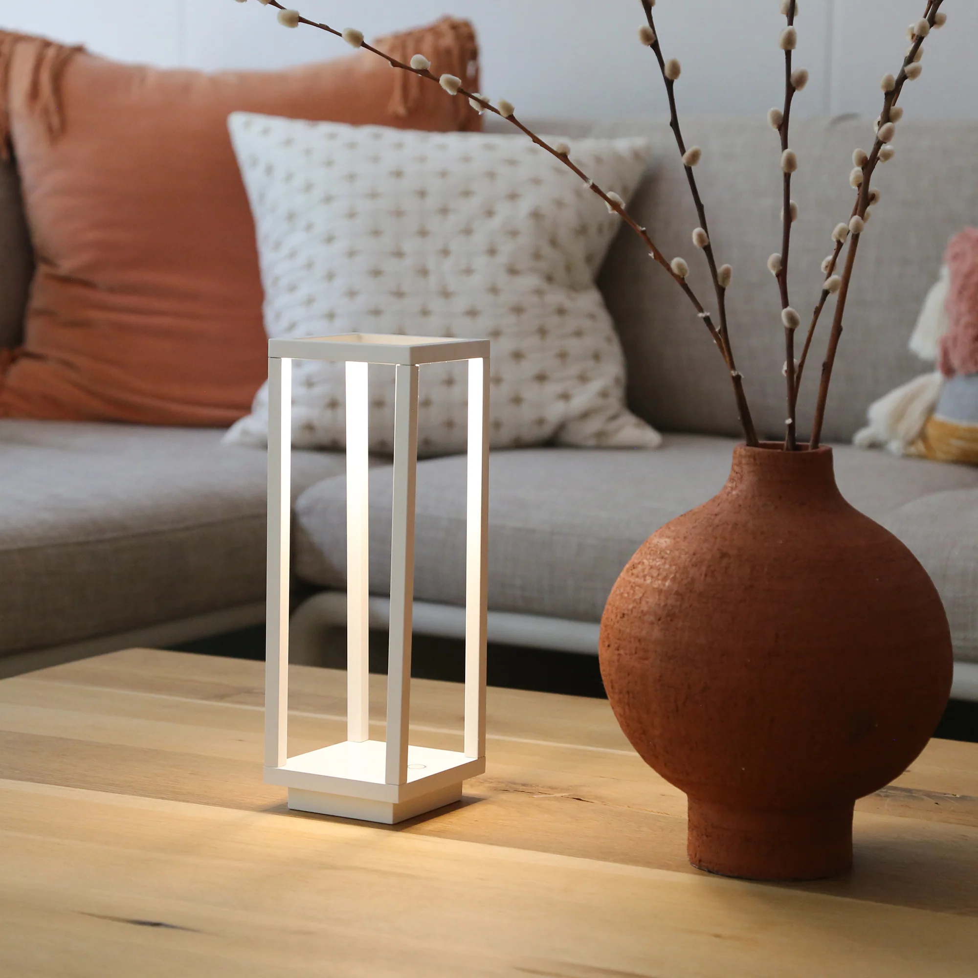 The white Home Cordless Lamp from Zafferano in a living room on top of a coffee table.