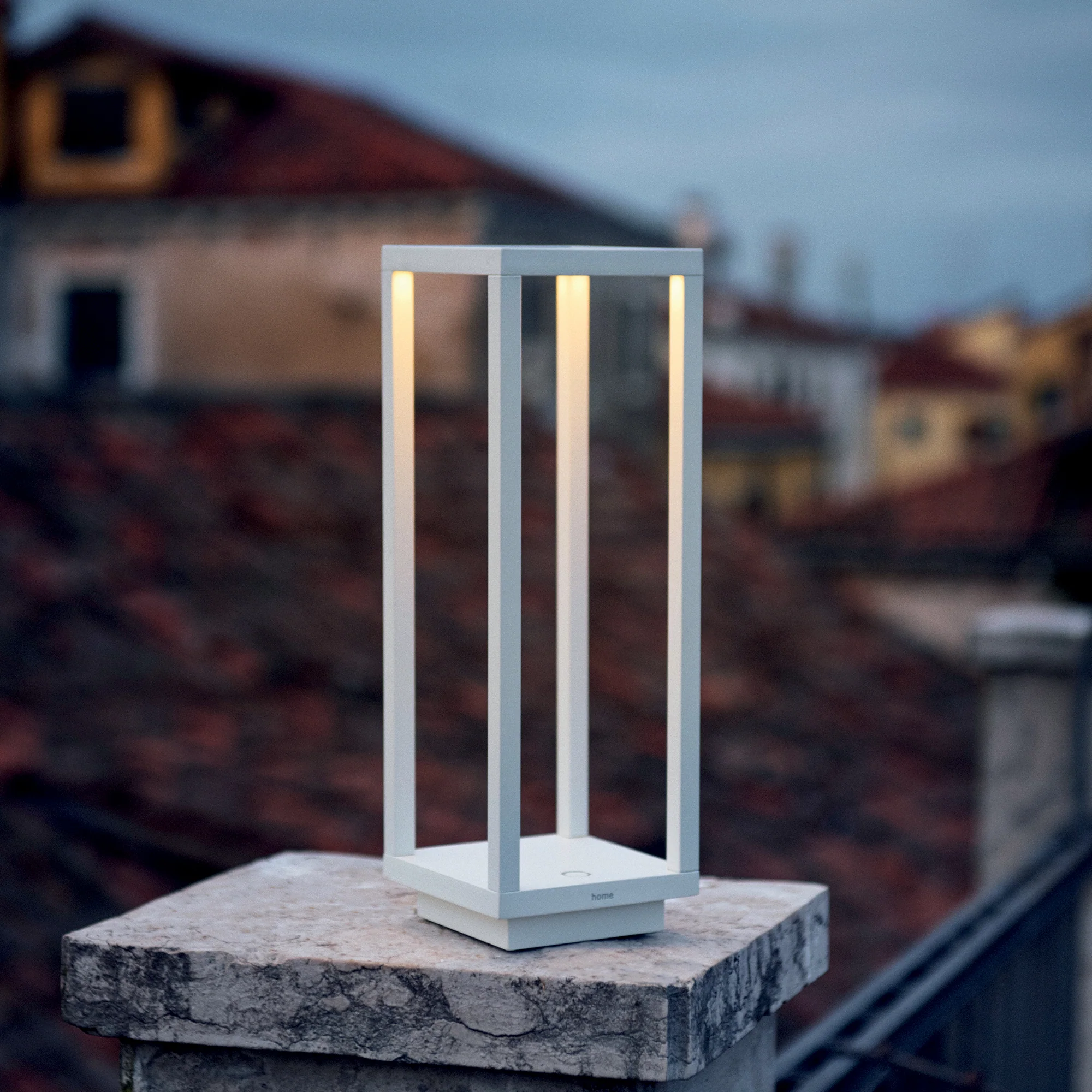 The white Home Cordless Lamp from Zafferano outdoors illuminating a pathway.