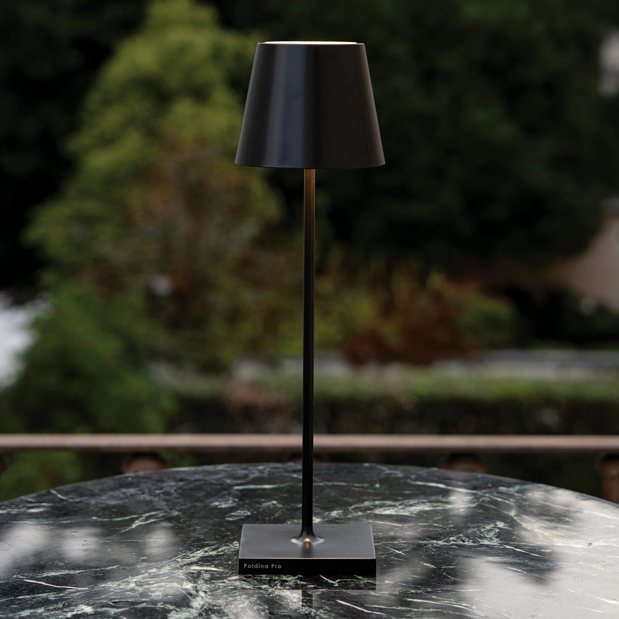 The black Poldina Pro from Zafferano in a garden on top of a black marble table.
