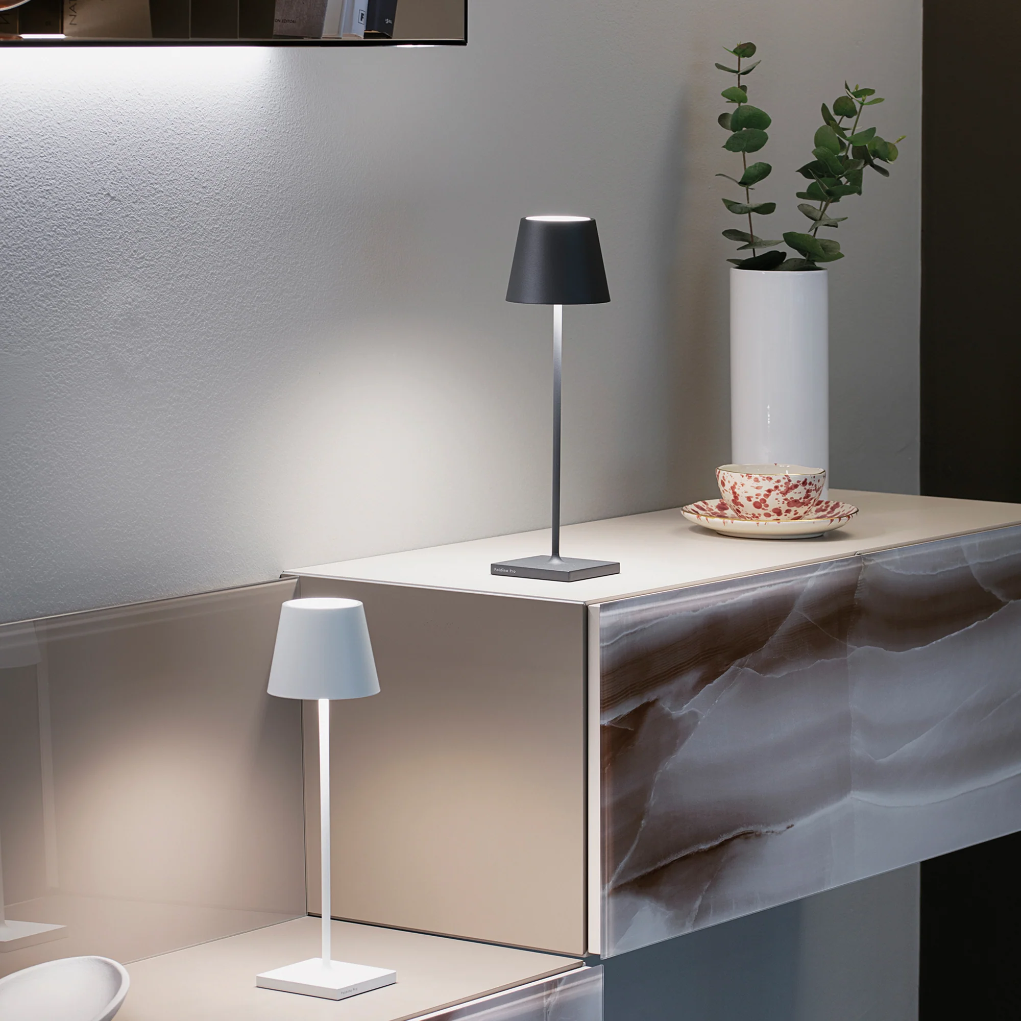 The dark gray Poldina Pro from Zafferano in a lounge on top of a shelf.