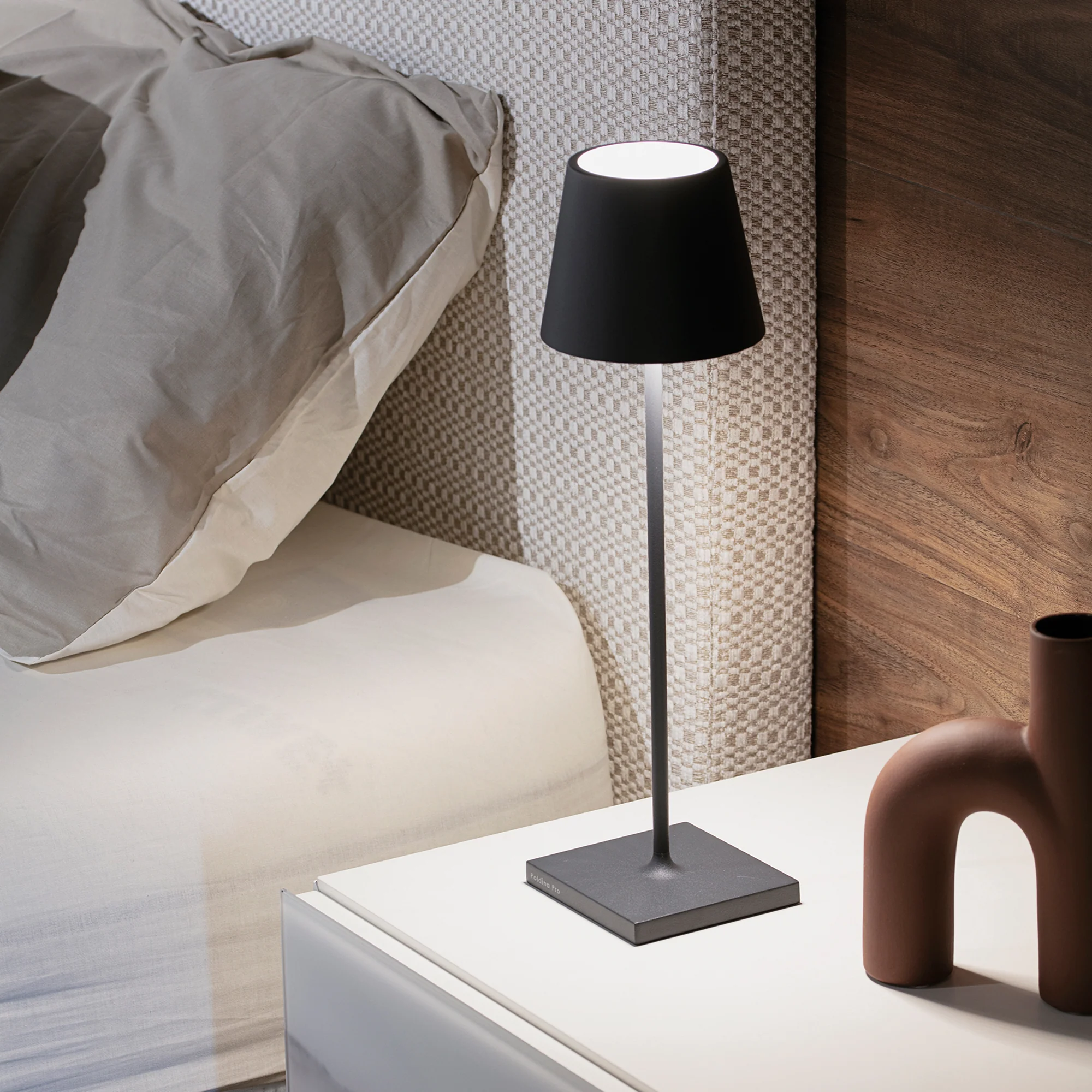 The dark gray Poldina Pro from Zafferano in a primary bedroom on top of a bedside table.