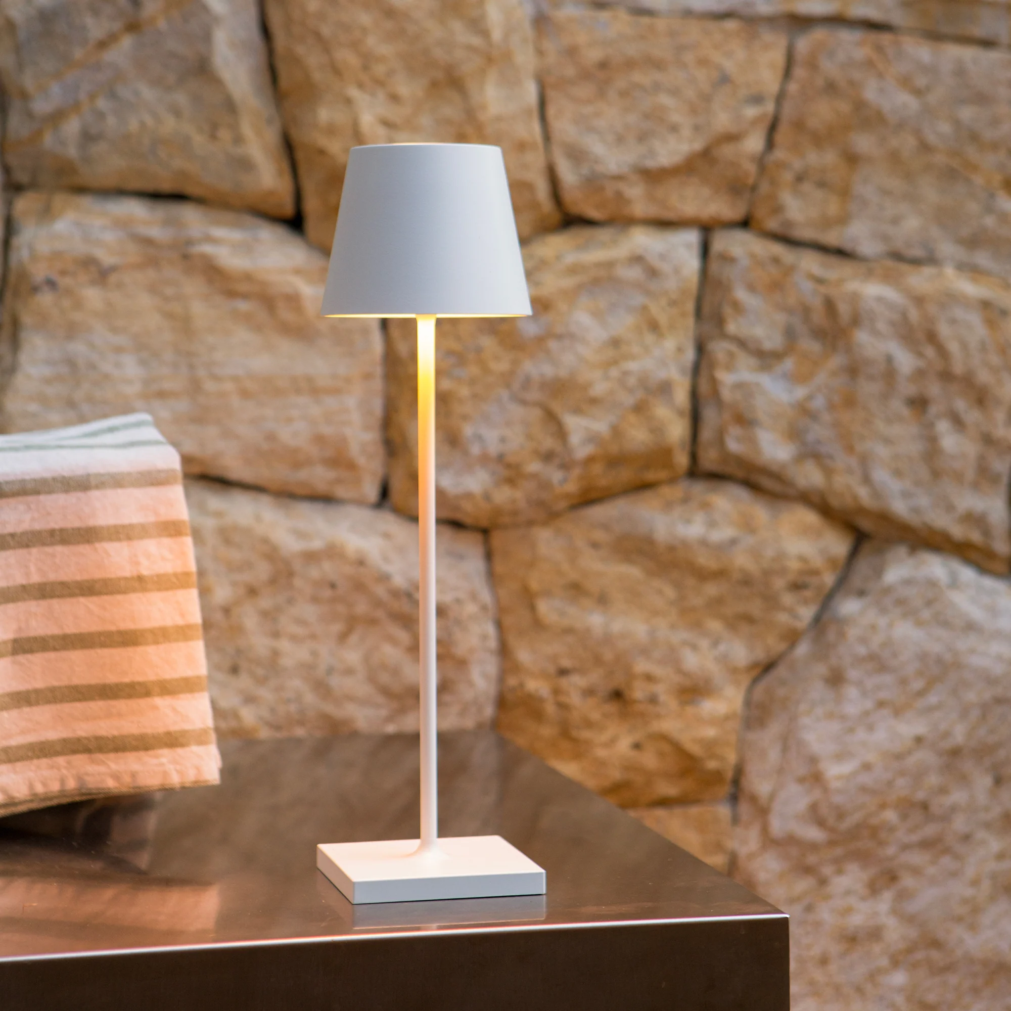 The white Poldina Pro from Zafferano in a primary bedroom on top of an end table.