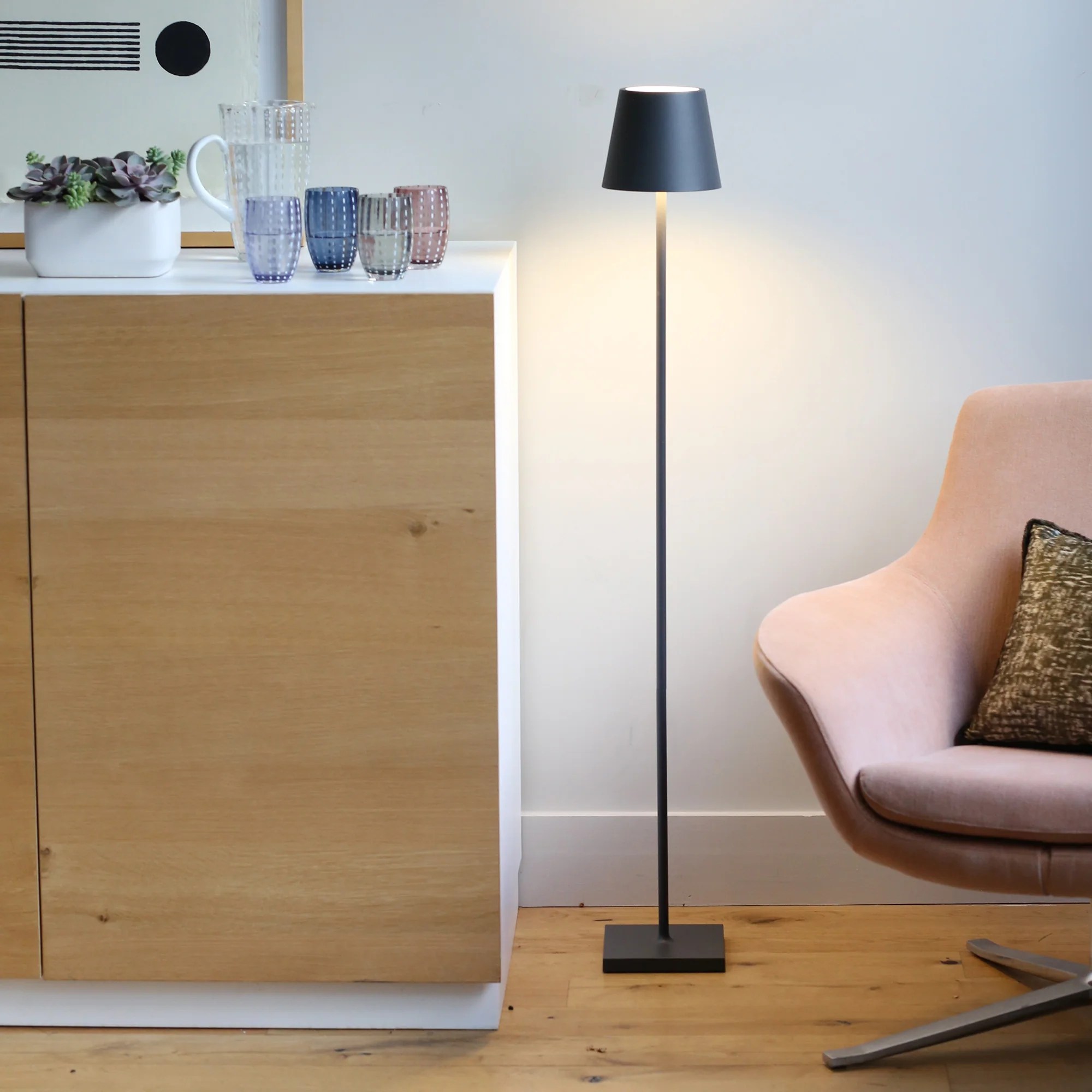 The dark gray Poldina Pro L Floor Lamp from Zafferano in a living room between a cabinet and a chair.