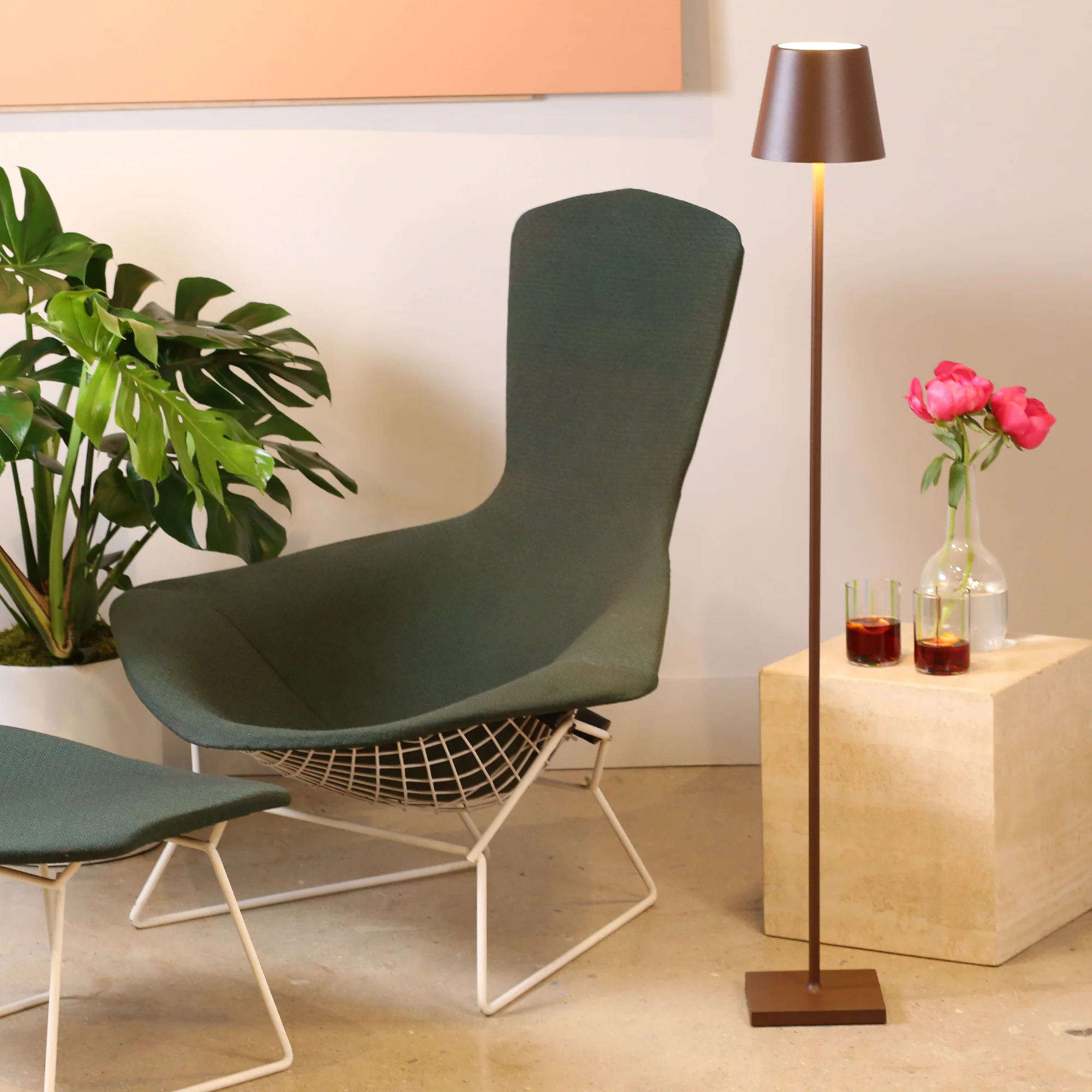 The rust Poldina Pro L Floor Lamp from Zafferano in a living room beside a lounge chair and ottoman.