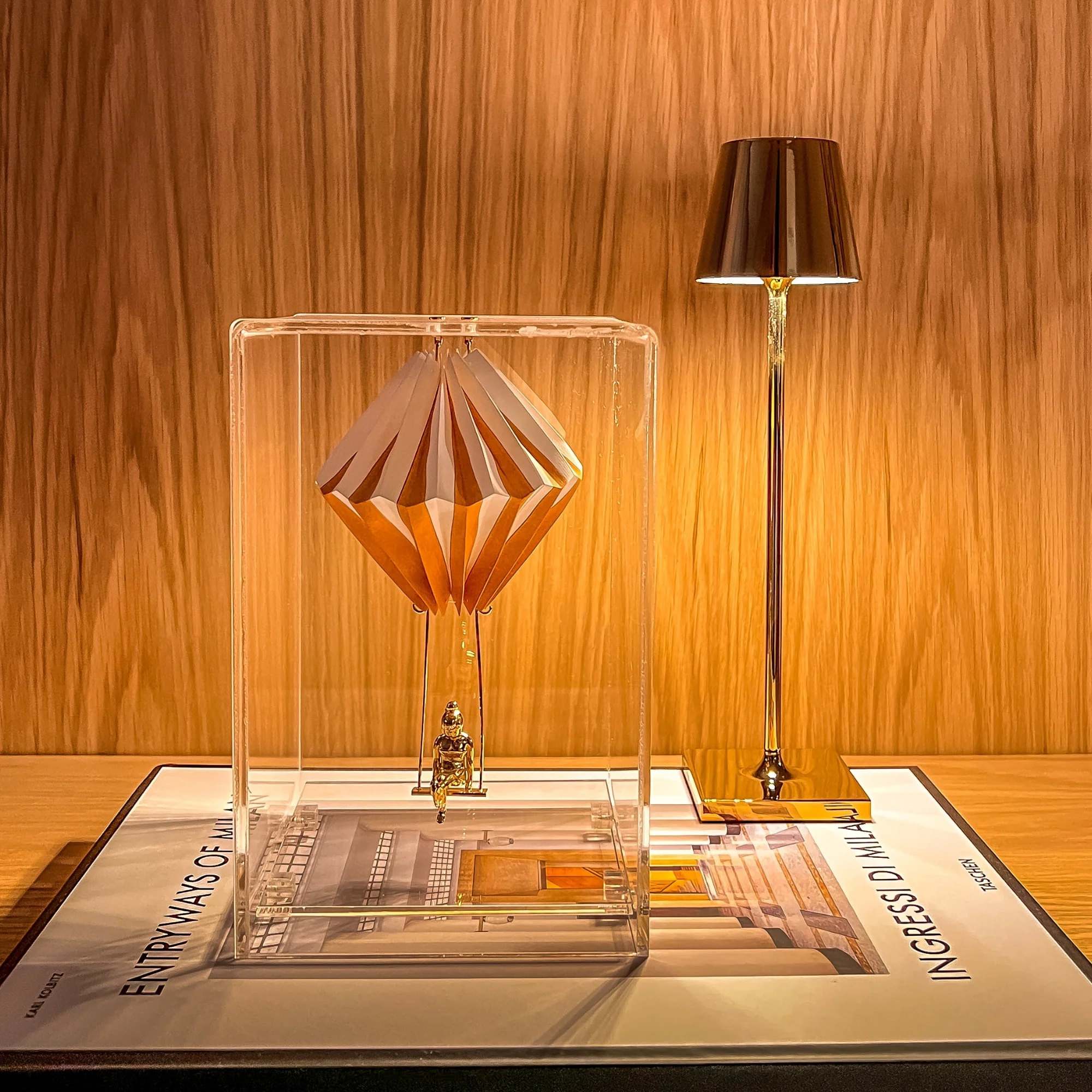 The glossy gold Poldina Pro Micro Cordless Lamp from Zafferano in a home office next to a golden sculpture.