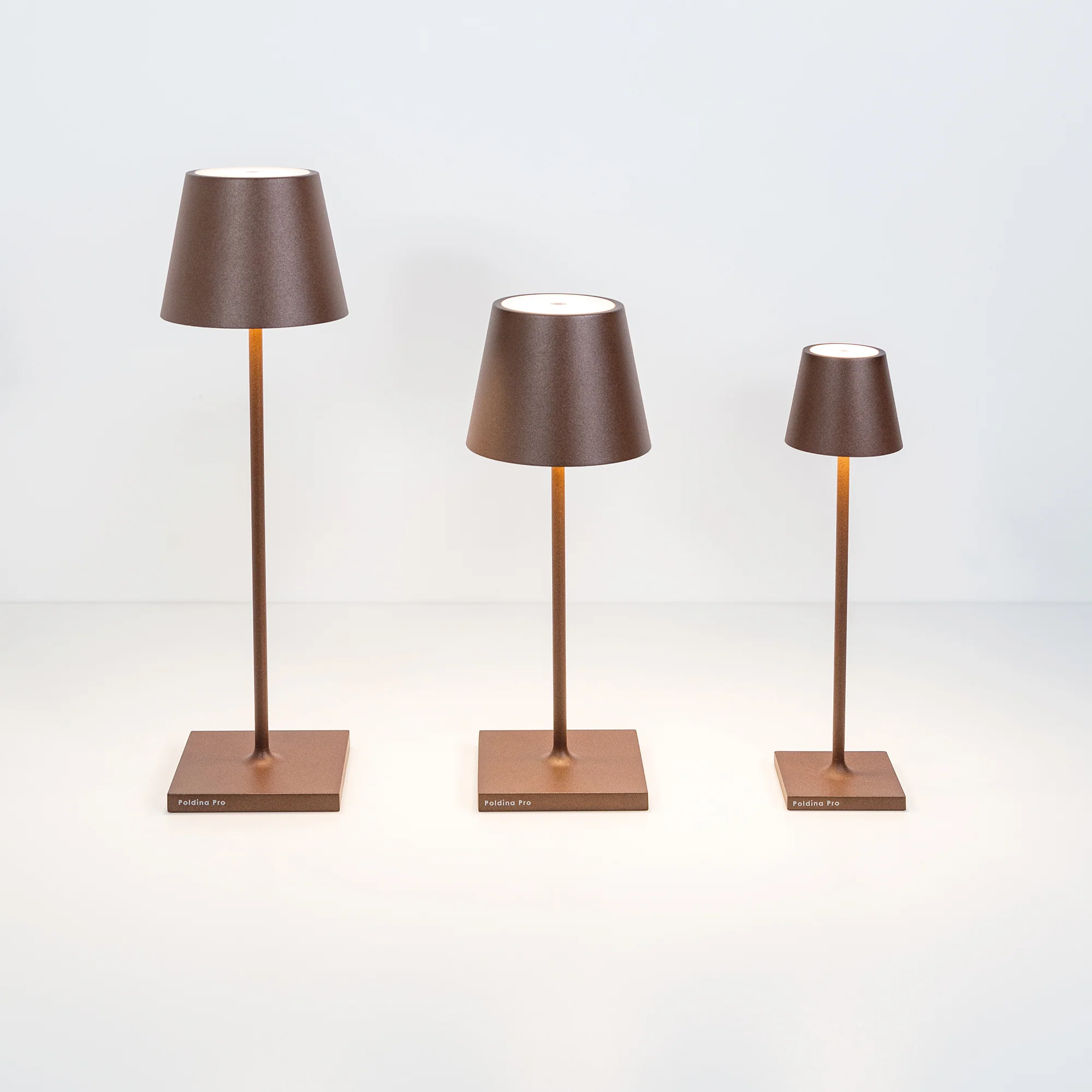 The rust Poldina Pro Micro Cordless Lamp from Zafferano with the other sizes of the Poldina Lamp.