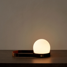 The bronzed brass Carrie Portable Table Lamp from Audo Copenhagen showing the adjustable handle and it's functionality.
