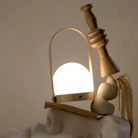 The brushed brass Carrie Portable Table Lamp from Audo Copenhagen in a lounge with various decor and sculptures.
