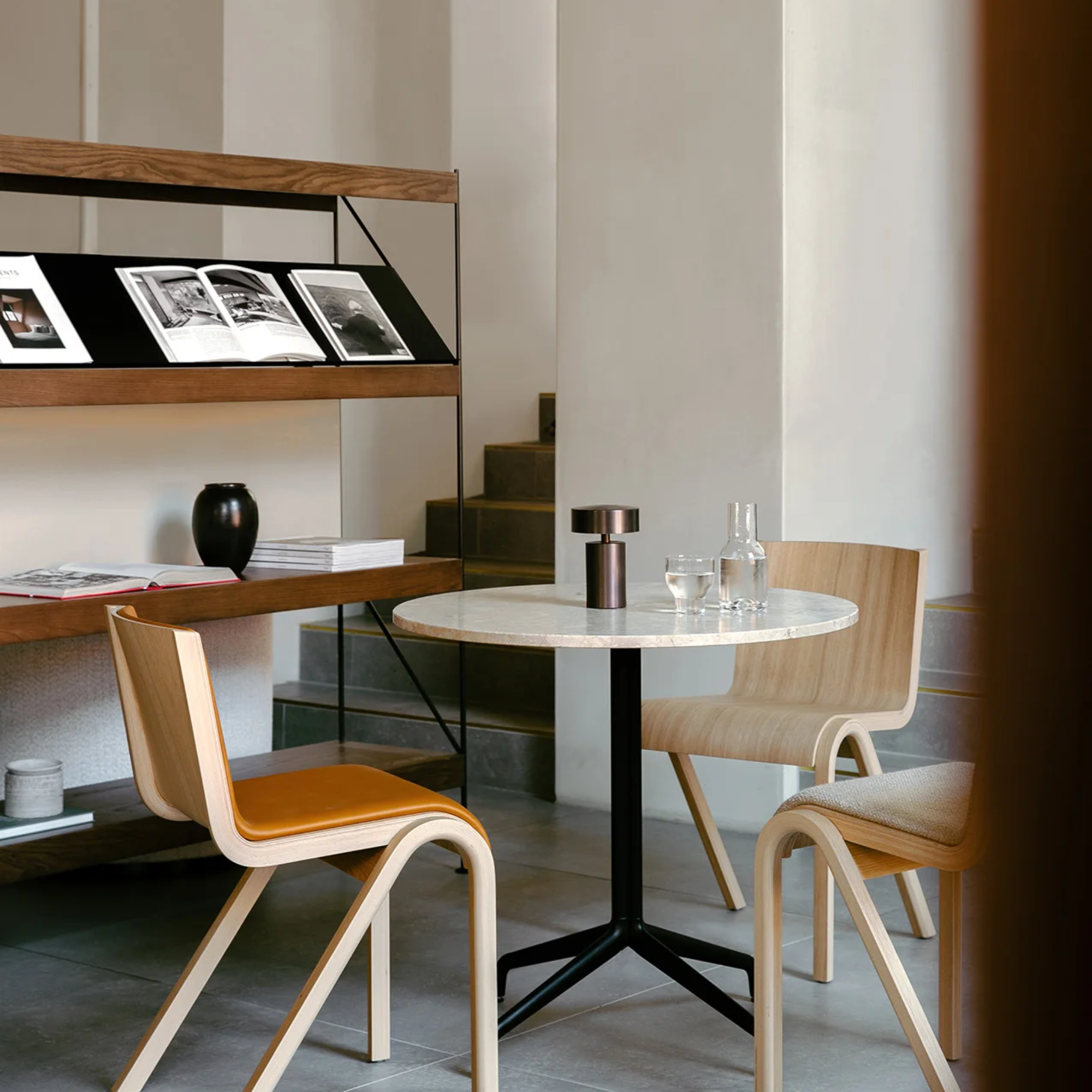 The bronze Column Portable Table Lamp from Audo Copenhagen on a table in a cafe space.