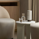 The Hashira Portable Table Lamp from Audo Copenhagen in a living space on an end table with a water carafe.