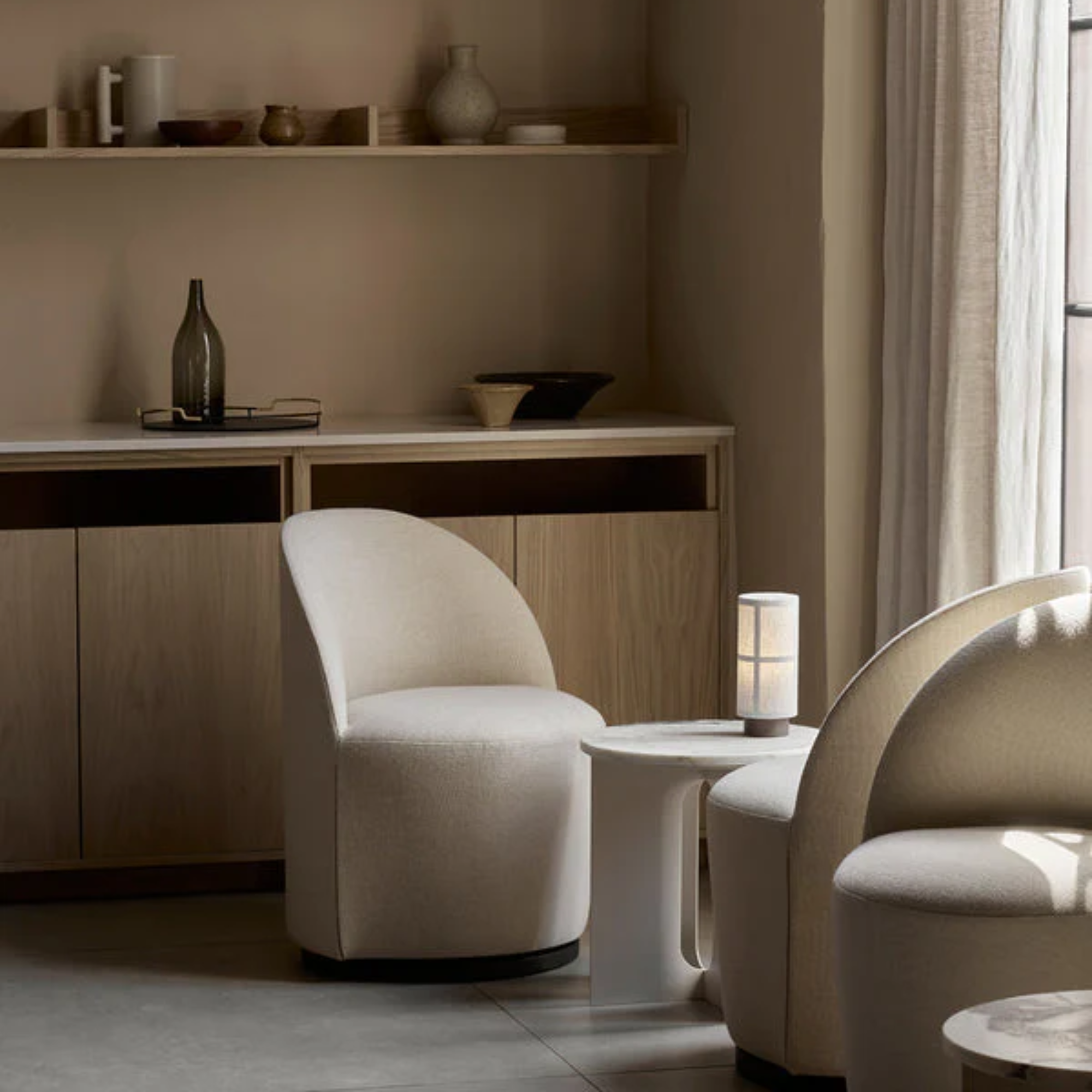 The Hashira Portable Table Lamp from Audo Copenhagen in a lounge with various chairs, tables and decor.