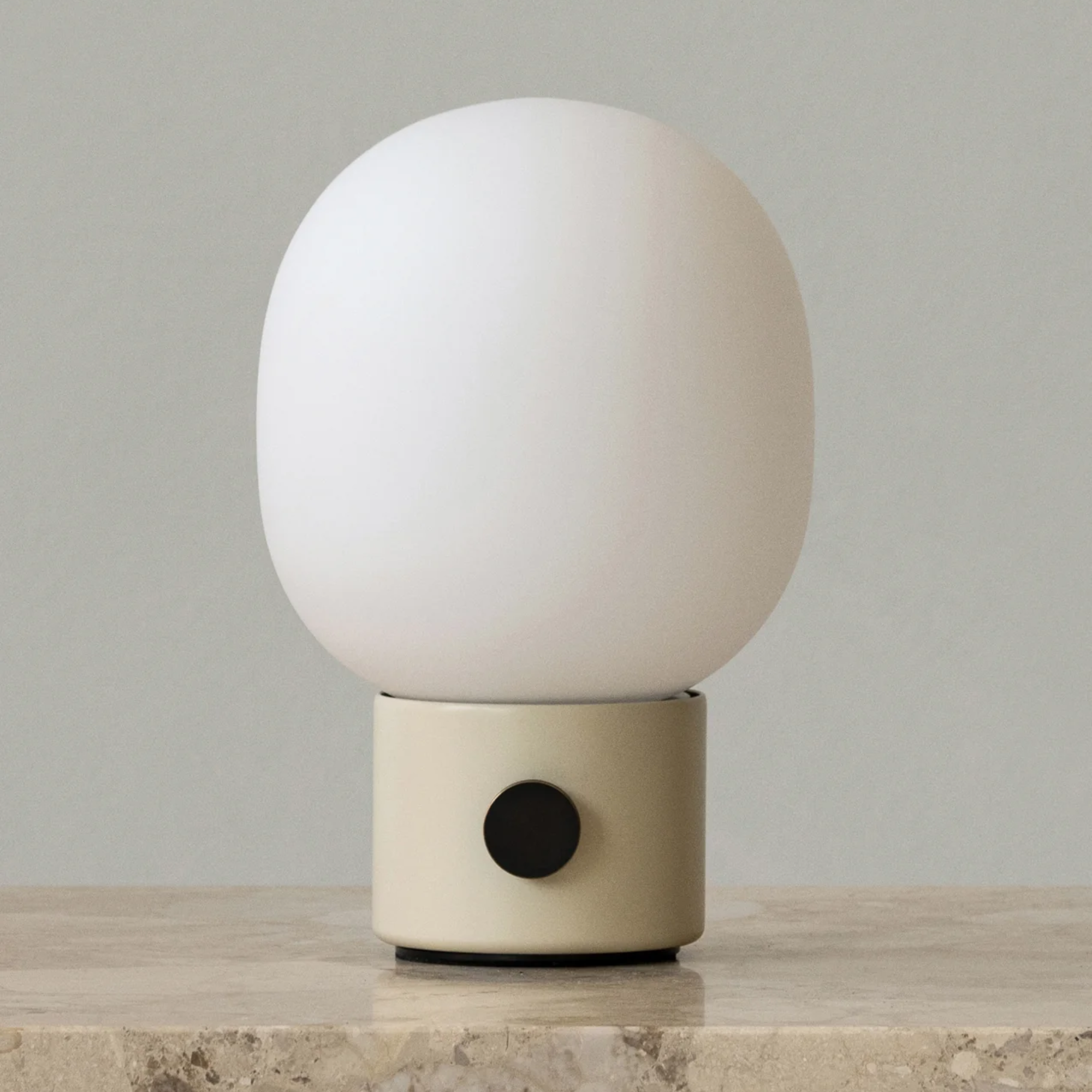 The alabaster white JWDA Portable Table Lamp from Audo Copenhagen in a living space on top of a marble table top.