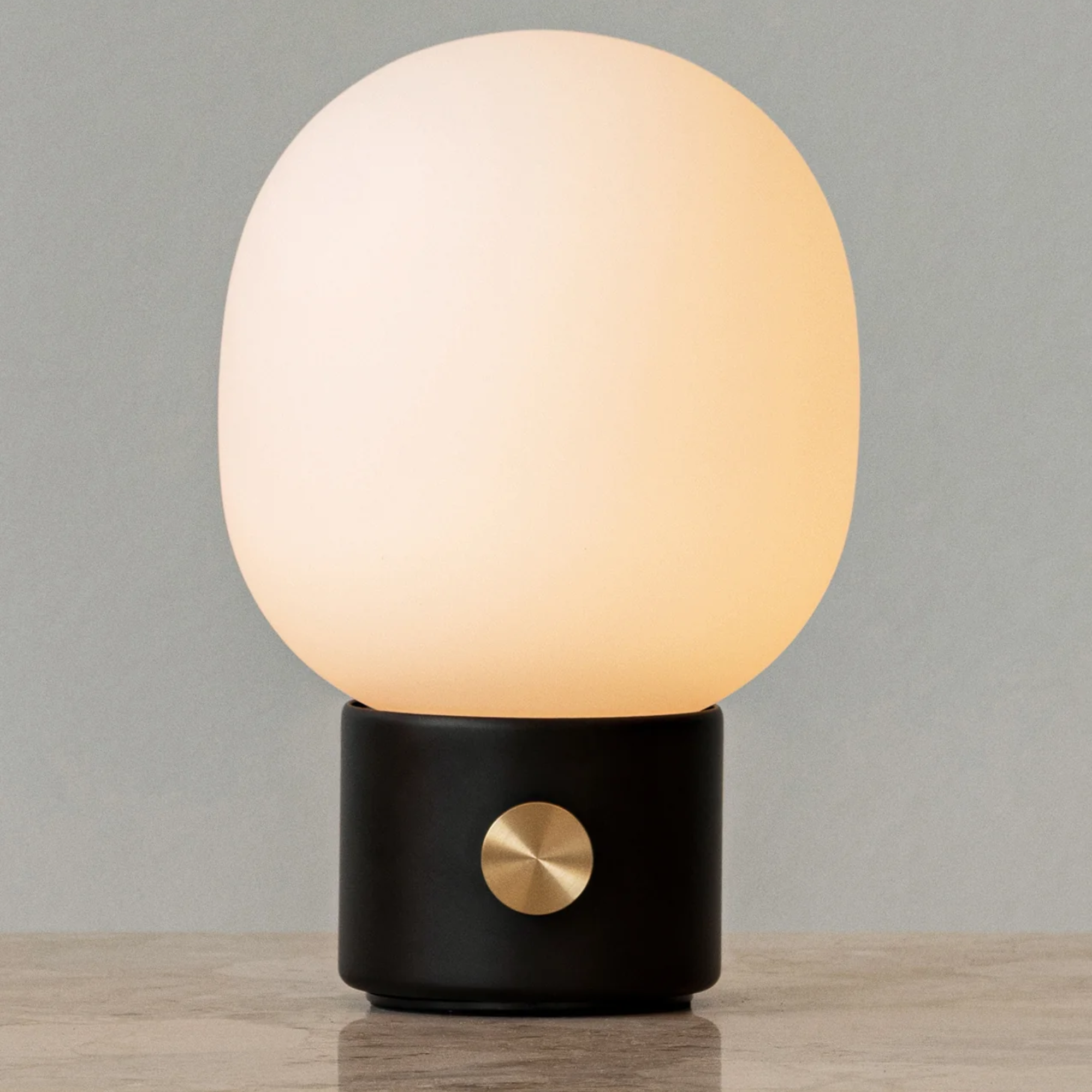 The black JWDA Portable Table Lamp from Audo Copenhagen in a home office on top of a marble surface.
