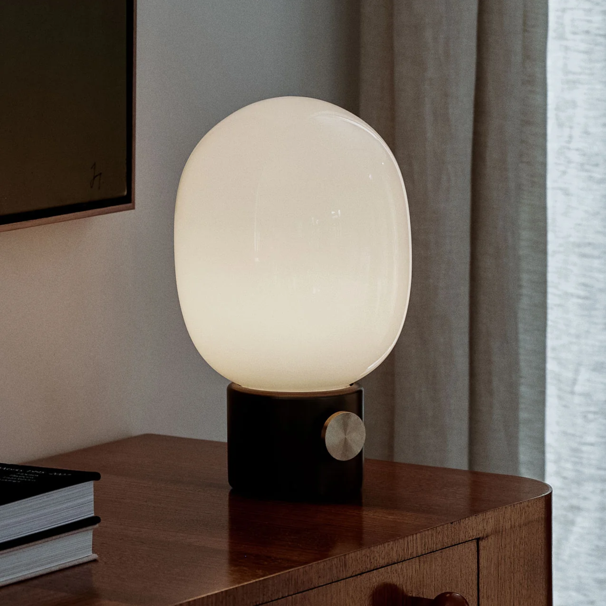 The black JWDA Portable Table Lamp from Audo Copenhagen in a living room on top of a table.