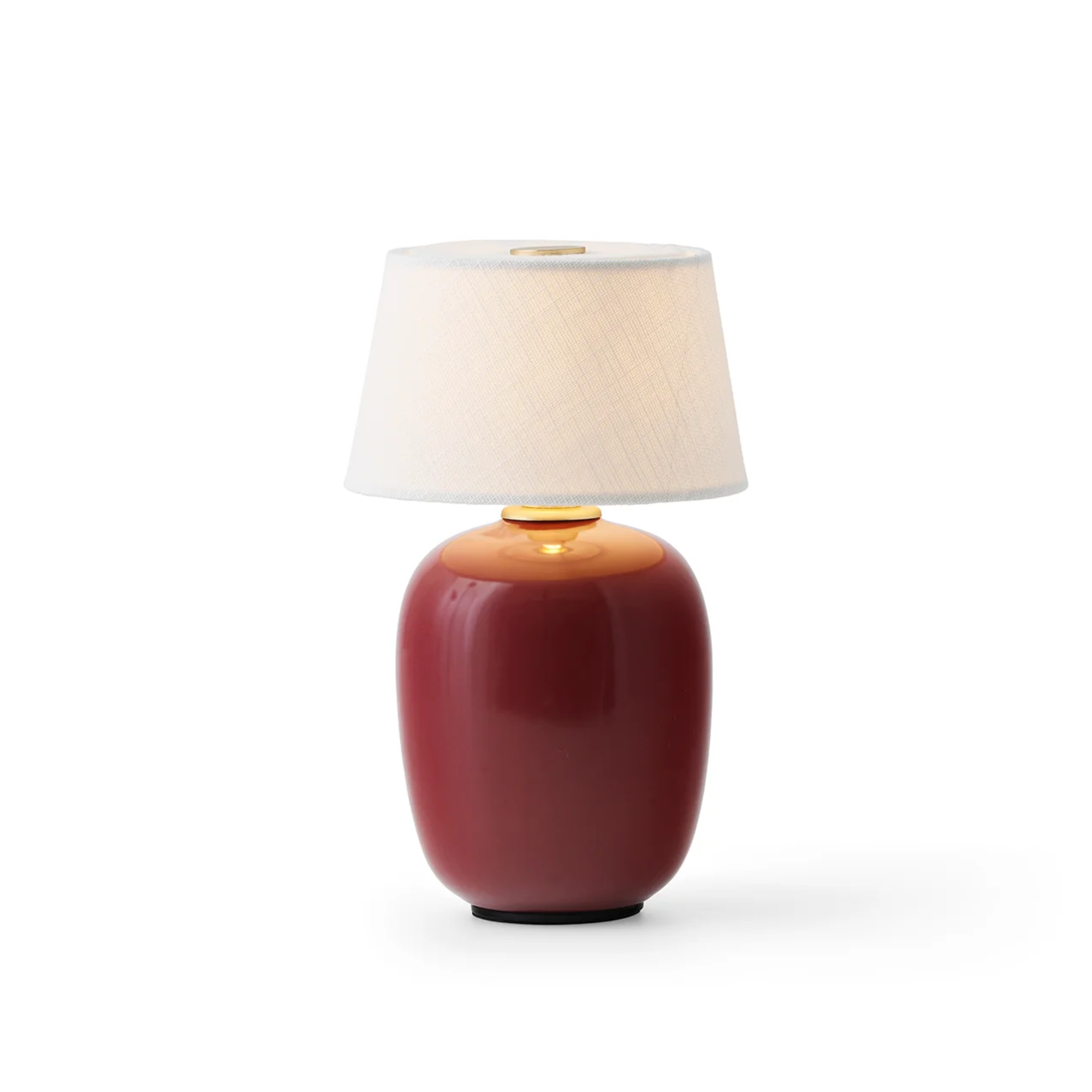 The ruby Torso Portable Table Lamp from Audo Copenhagen turned on.